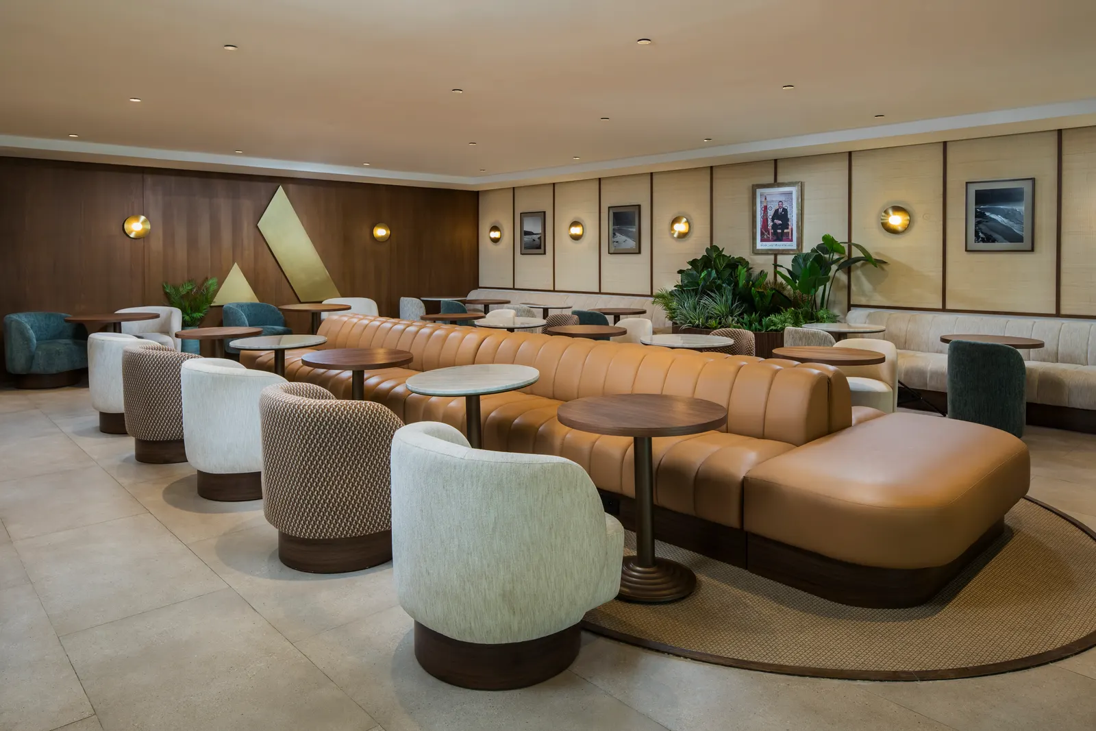 Curved tan banquette and modern armchairs in the Agadir Aspire Lounge at Agadir–Al Massira Airport (AGA).