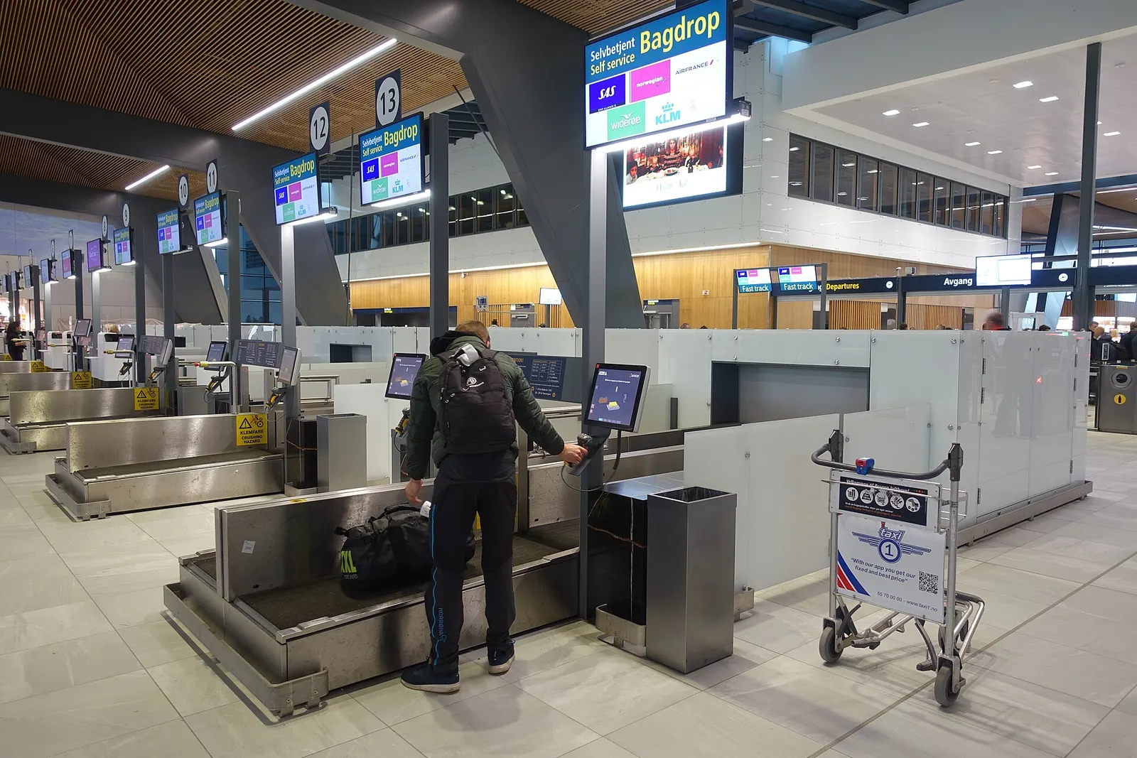 Self-service Bag drop for registration and sending checked bags and luggage: a self-check-in process allowing passengers with bags to check-in at Self Bag Drop machines where they attach the baggage tag and drop the bag at the baggage drop belt (conveyor belt). Photo taken at the departure terminal