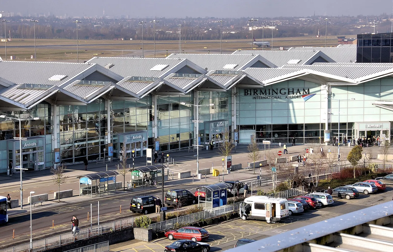 Part of Terminal 2 at Birmingham International Airport, England, taken from the top level of a multi-storey car park. The runway is seen beyond, with an Air Malta aircraft. Notice the concrete blocks that seal off the road alongside the terminal, for security reasons. This means that passengers and