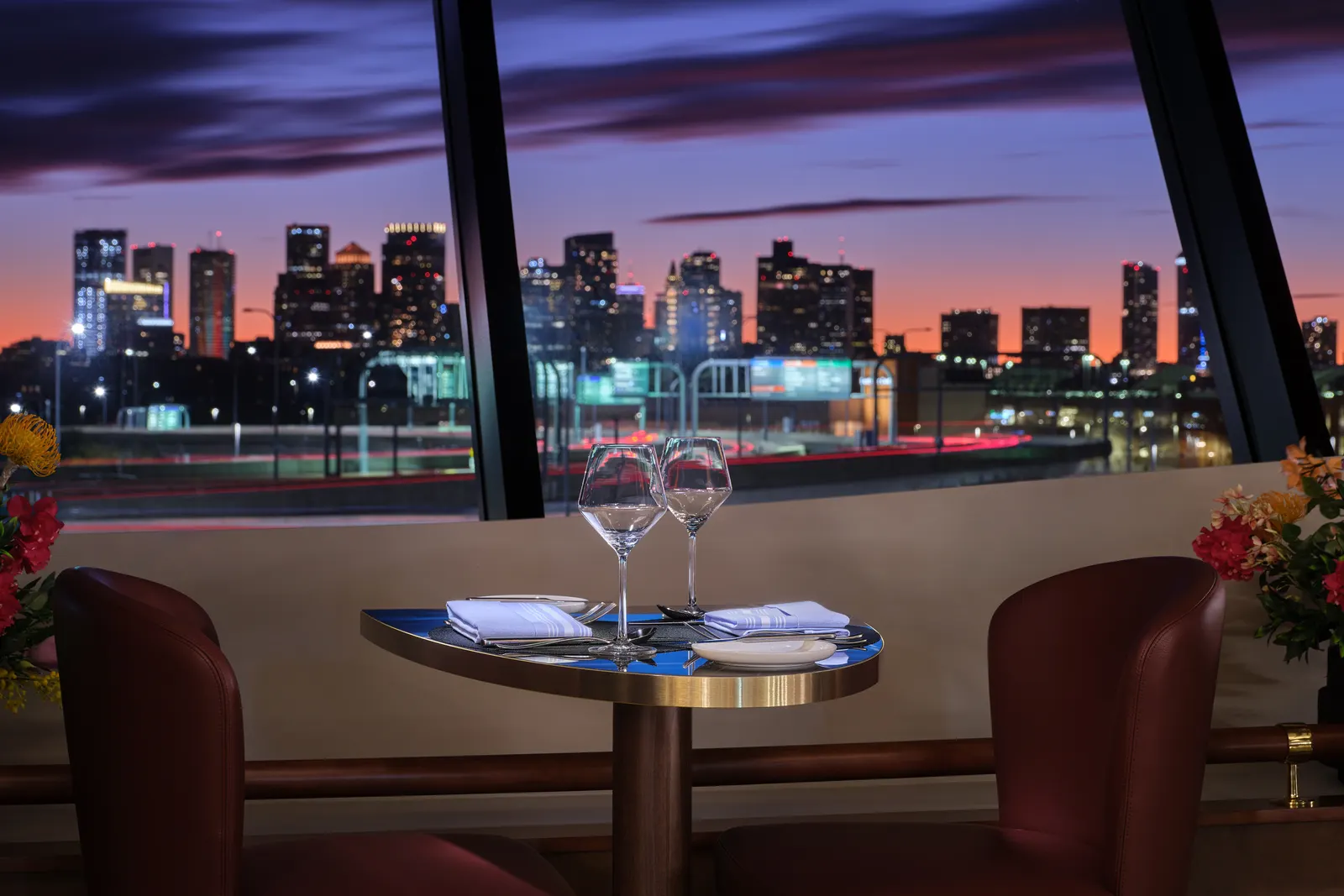 Dining table detail with harbor-facing windows at sunset in the Delta One Lounge at Boston Logan (BOS).