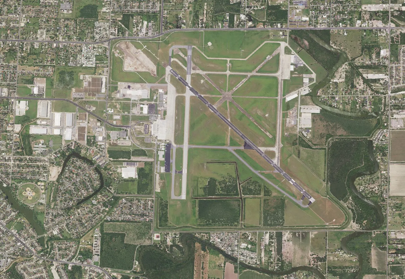 USGS NAIP aerial of Brownsville/South Padre Island International Airport showing runway 13/31, runway 18/36, and the east-side passenger terminal.