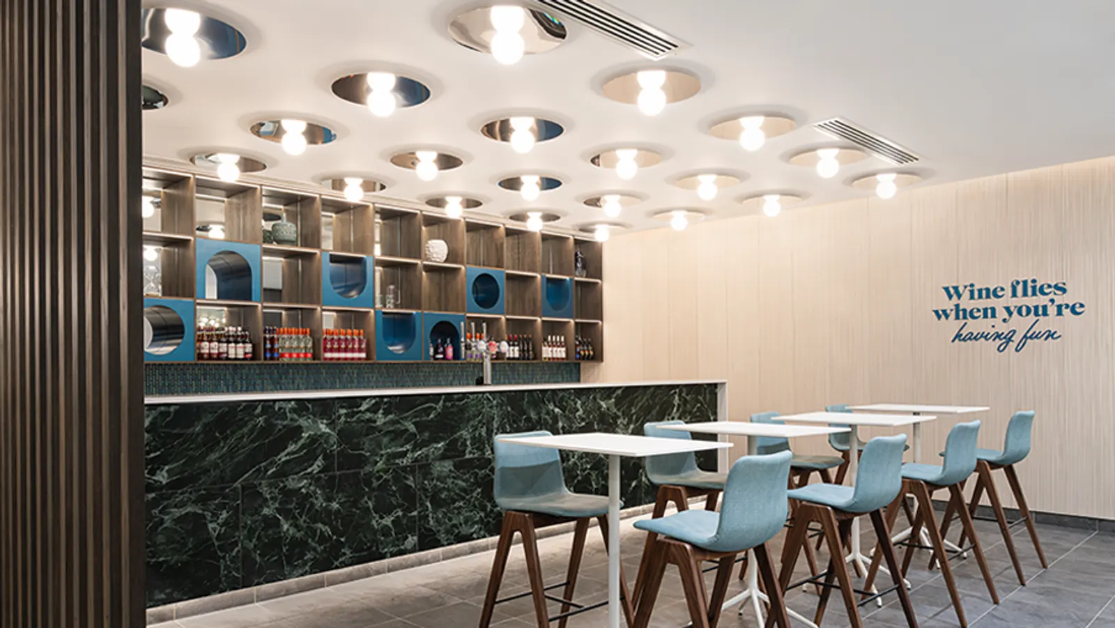 Green marble bar with blue arched niches and high-top seating in the Escape Lounge at Bristol Airport (BRS).