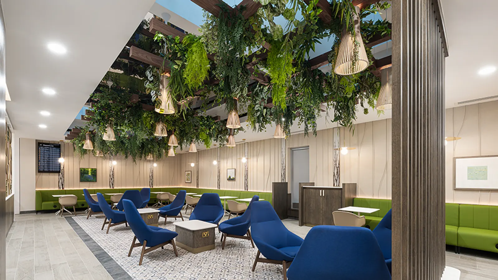 Clusters of dark blue armchairs under hanging plants and circular ceiling lights in the Escape Lounge at Bristol Airport (BRS).