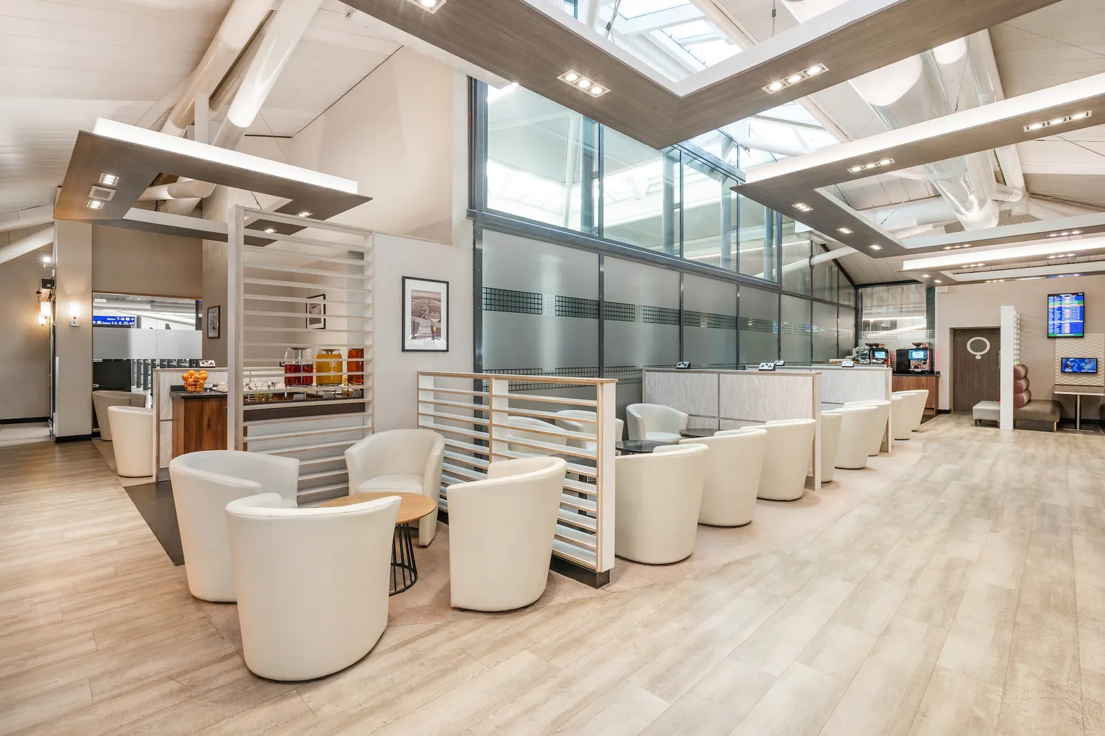 White tub chairs and high-walled seating pods under a vaulted beamed ceiling in Essence by Escape Lounges at Bristol Airport (BRS).