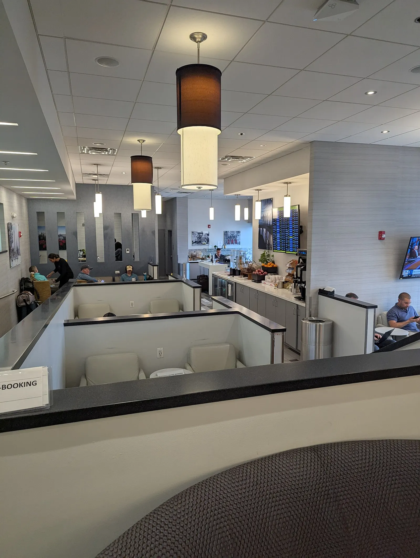 The interior of "The Club" BWI airport lounge with seating in the center and a counter with fruite and drinks on the back left. The Club BWI is located in Concourse D near Gate 10. 7160 Aviation Blvd, Baltimore, MD 21240.