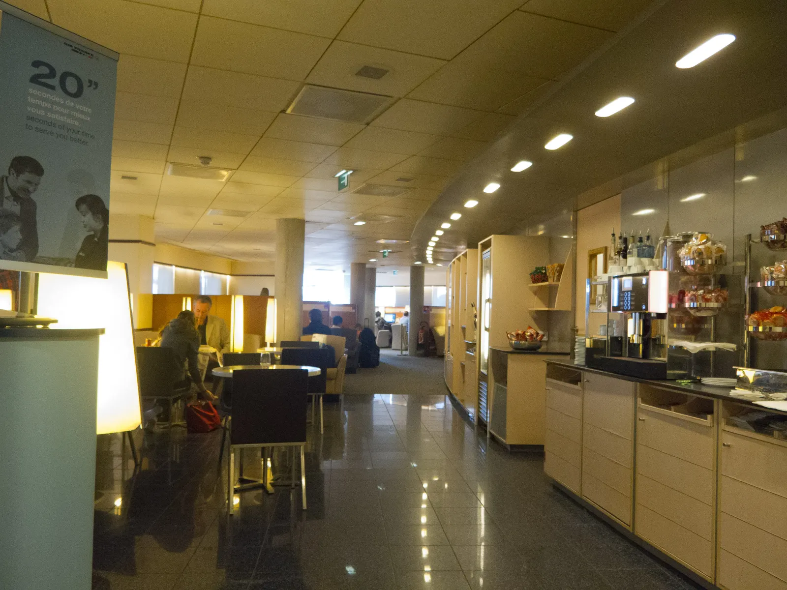 Coffee counter, snack jars, and lounge seating with frosted-glass dividers inside the Air France Lounge at Paris Charles de Gaulle Terminal 2E (CDG).