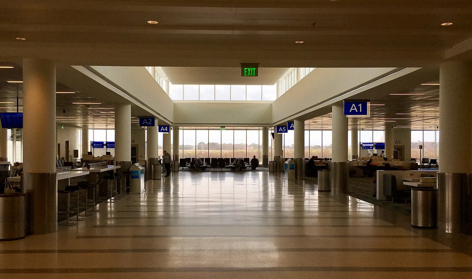 Open Concourse A holdroom at Charleston International with hanging gate signs A1, A2, A4 and A5 and floor-to-ceiling windows.