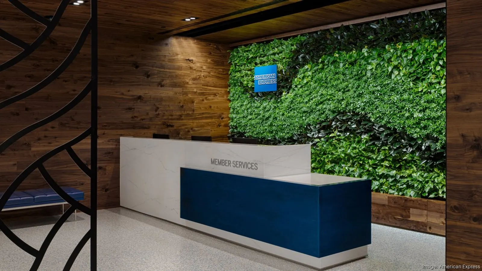 White and navy Member Services desk in front of a living green wall with wood paneling in the Centurion Lounge at Charlotte Douglas (CLT).