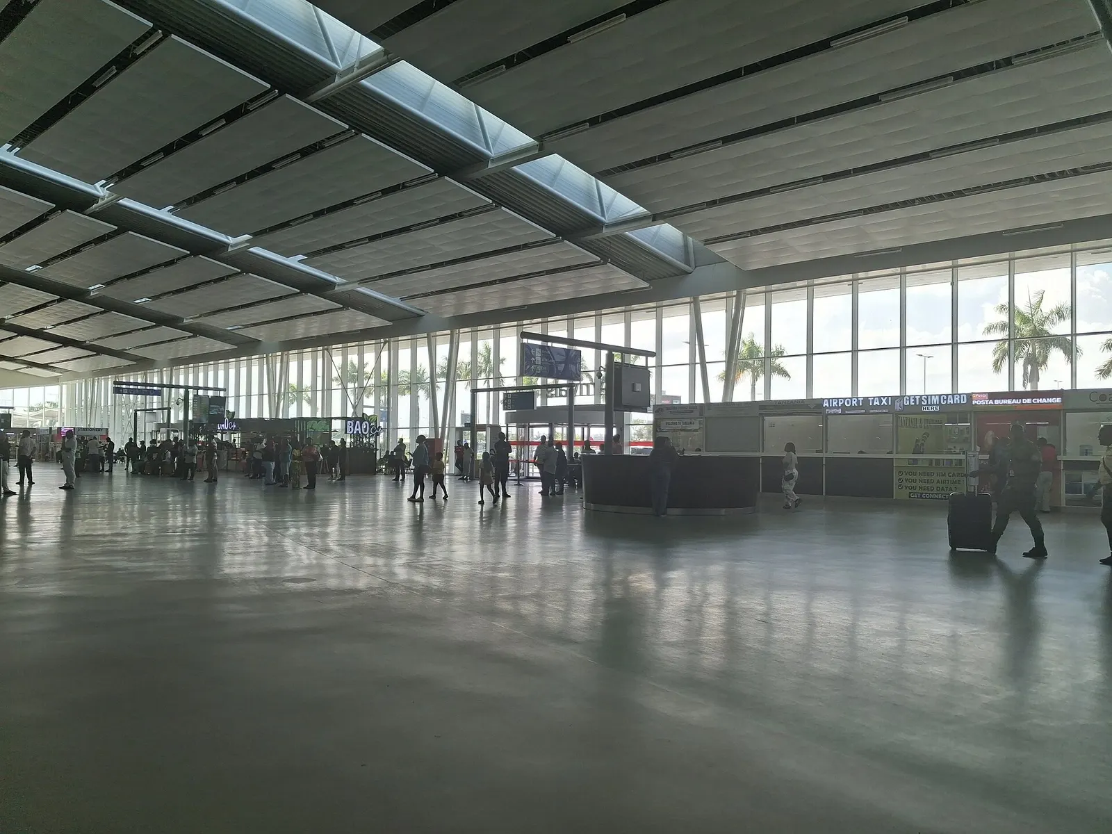Terminal 3 landside hall at Julius Nyerere International Airport with BAO Café, Airport Taxi desk, SIM card kiosk and bureau de change, December 2025