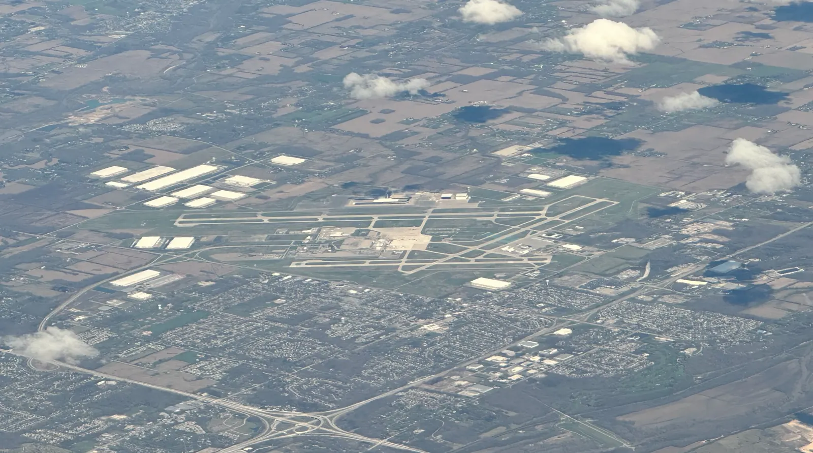 2024 aerial of James M. Cox Dayton International Airport taken from a commercial flight, showing the civil terminal, garage, and parallel runways.