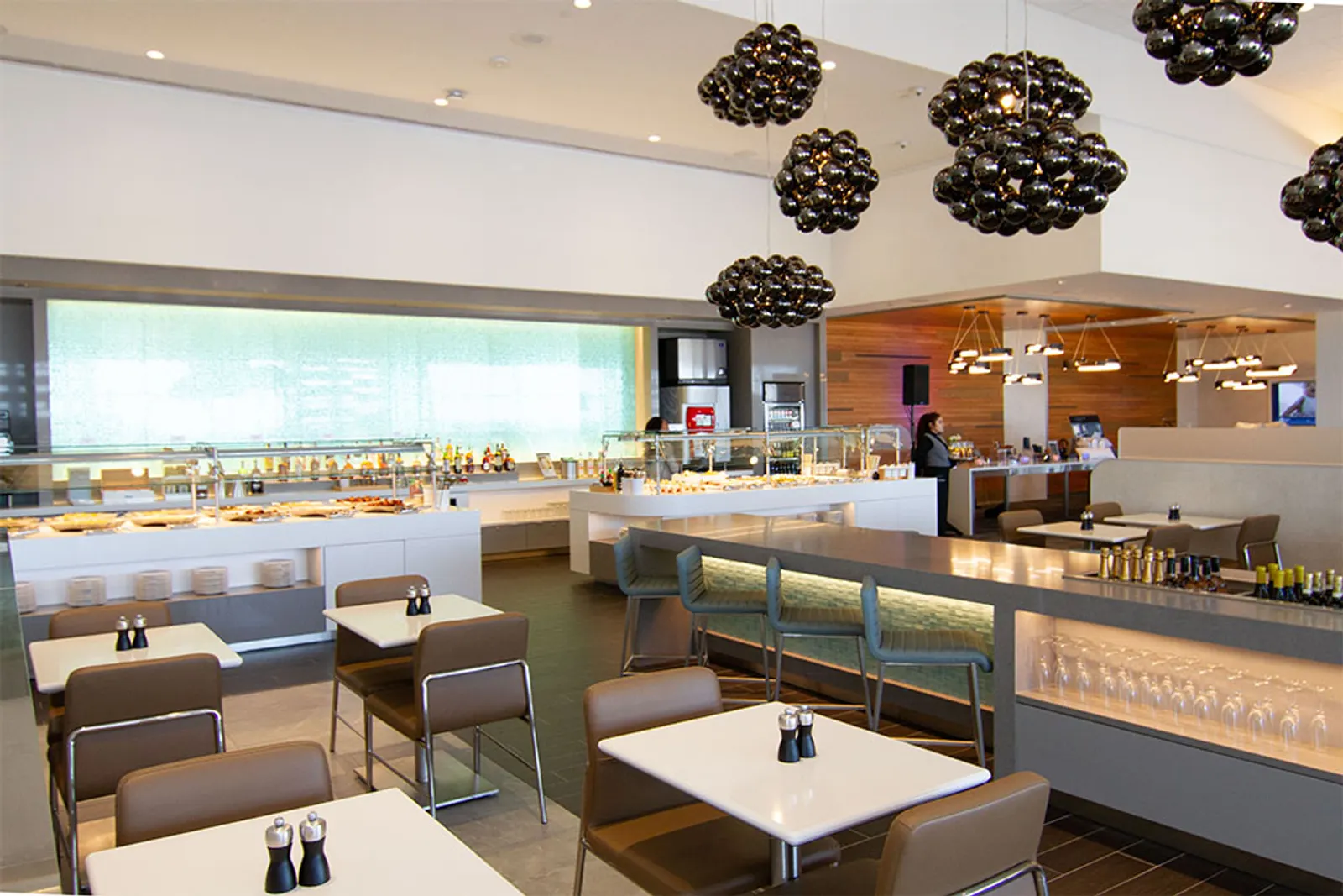 Bar and dining area under sculptural chandeliers in the American Airlines Flagship Lounge at Dallas Fort Worth International Airport (DFW) Terminal D.