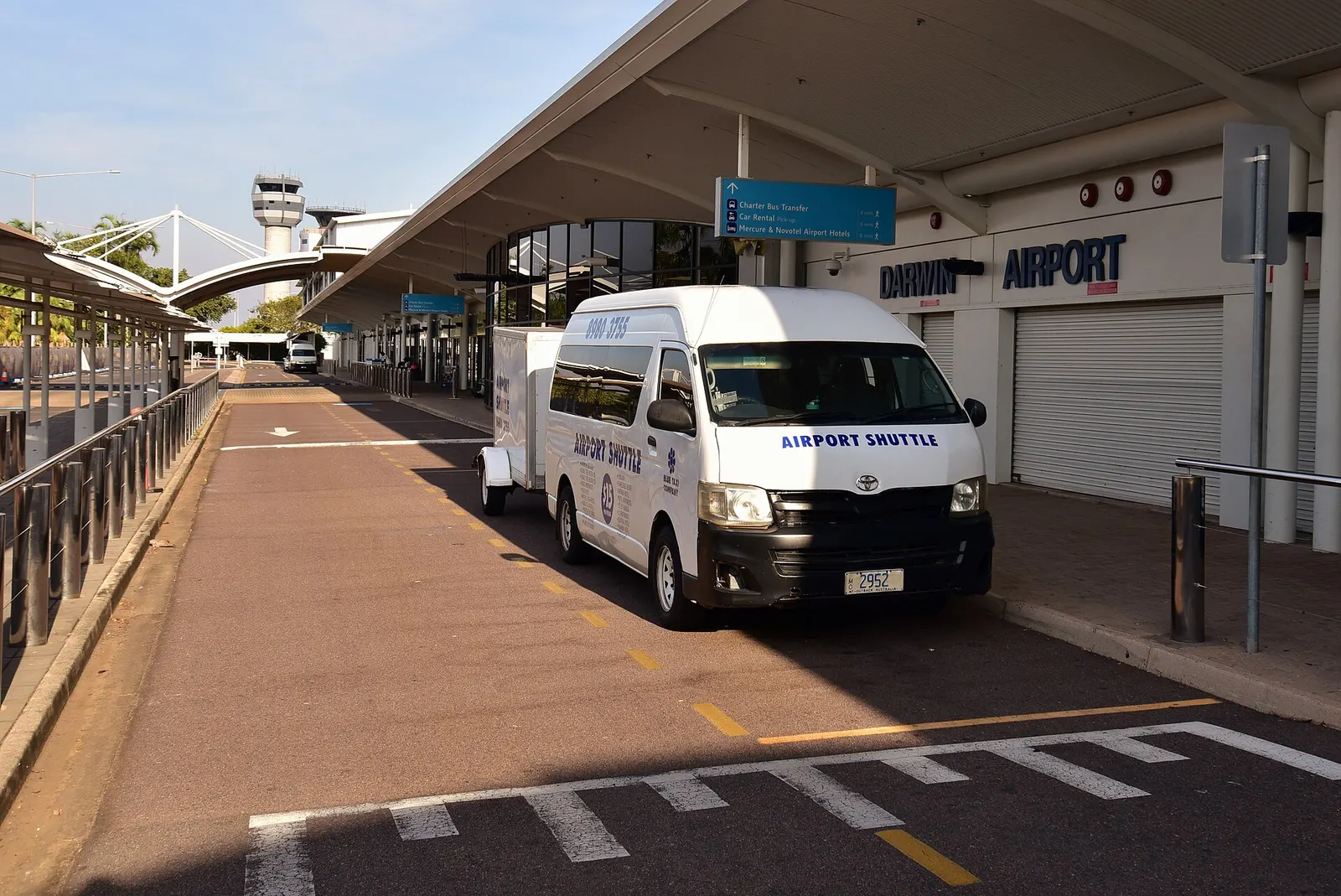 View of the terminal at Darwin International Airport , with a Toyota HiAce airport shuttle bus parked in front of it