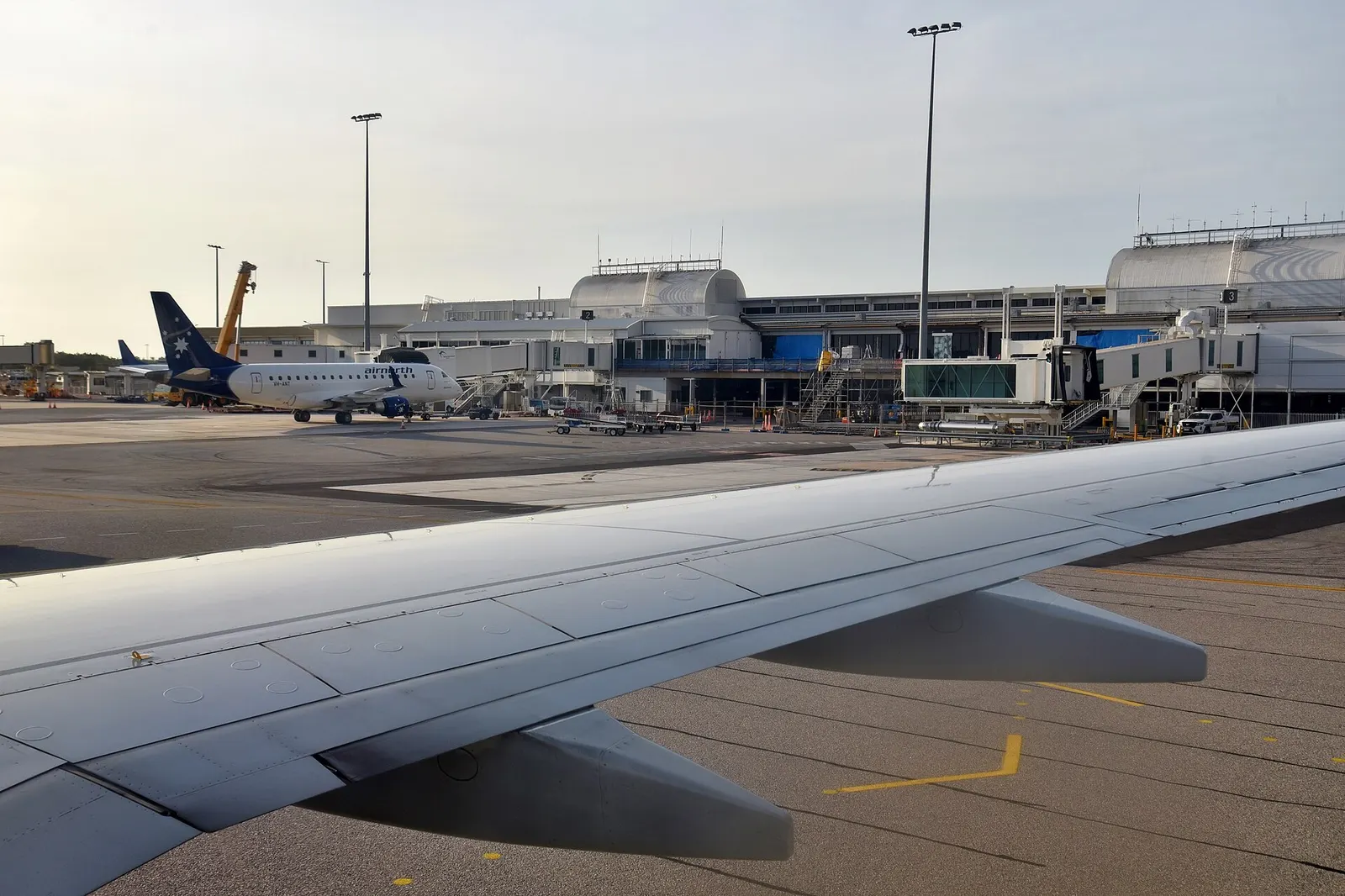 View of the terminal at Darwin International Airport (DRW/YPDN) from a starboard side cabin window of Virgin Australia Boeing 737-7K2 VH-NBV, in the lead up to its take off for Perth Airport (PER/YPPH), Western Australia, as VA1438