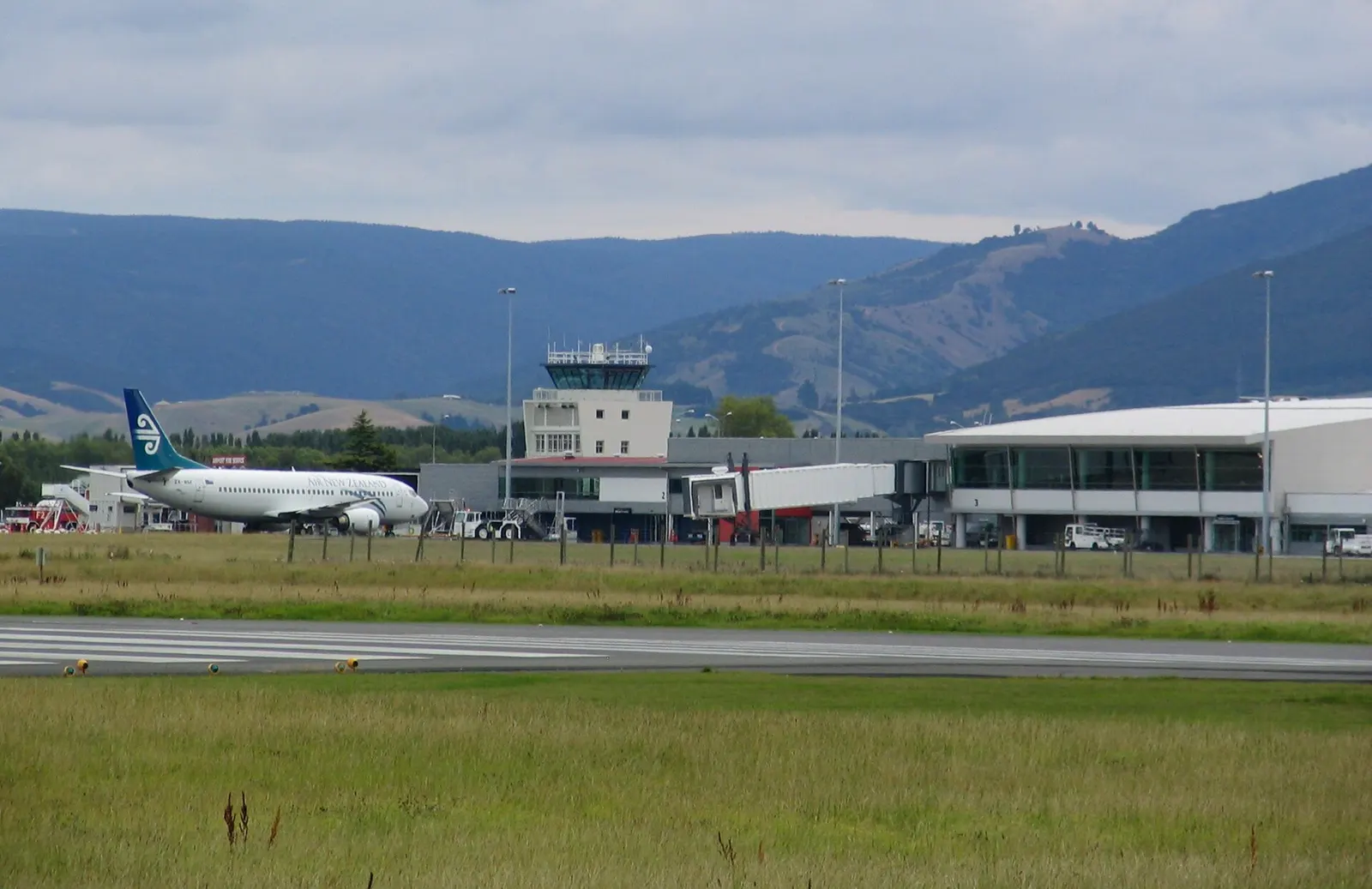 Dunedin International Airport , New Zealand (IATA: DUD, ICAO: NZDN), looking west showing control tower and terminal building. Air New Zealand Boeing 737-300 ZK-NGF being pushed back.