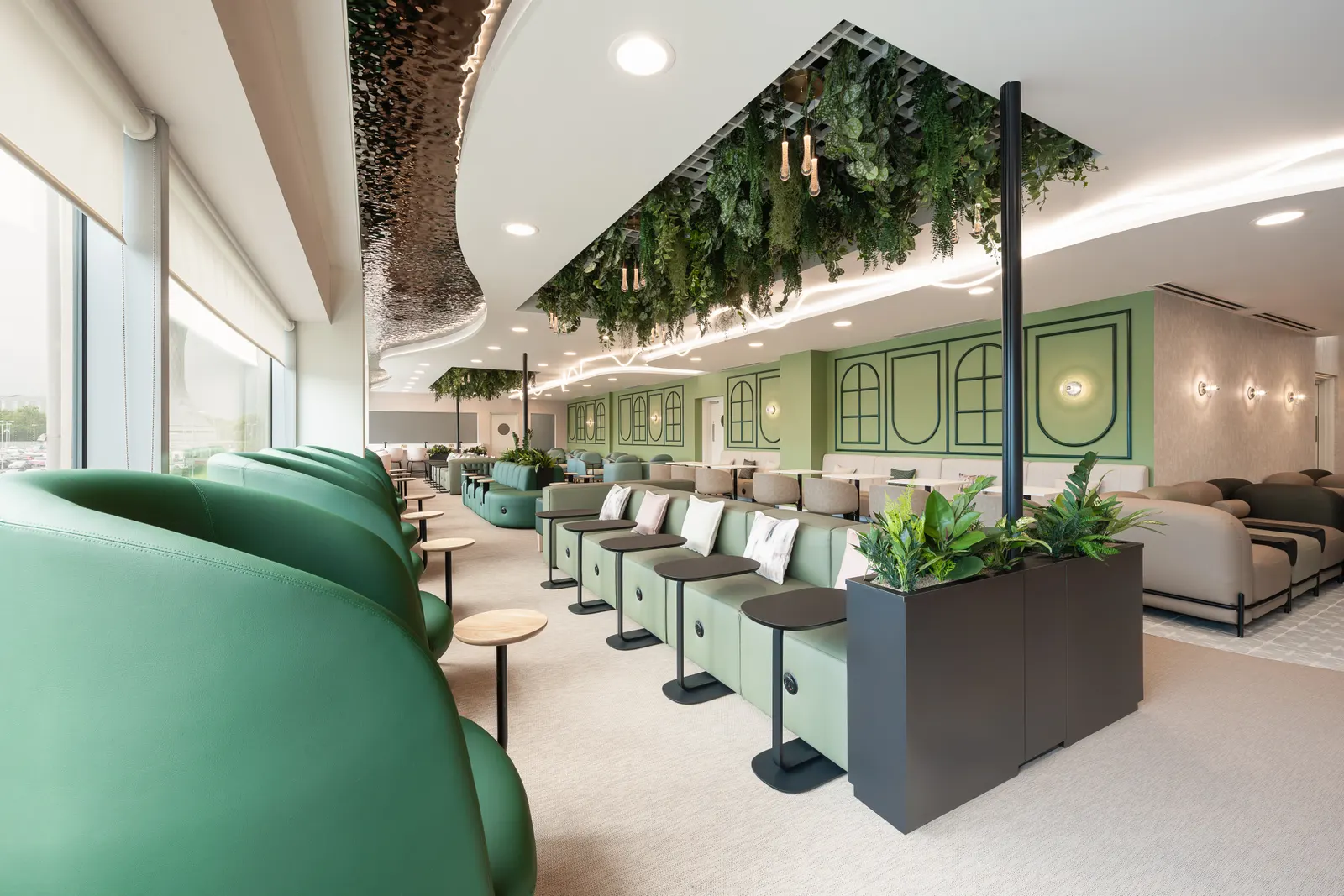 Green banquettes and grey armchairs under a hanging planter ceiling feature in the Escape Lounge at Edinburgh Airport (EDI).