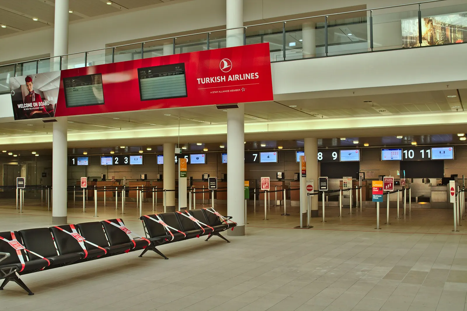 Departure hall of terminal 1 of Bremen Airport, deserted and with unmanned check-in counters during the Covid-19 crisis. Only one passenger aircraft per day departs here. On the bench in the foreground, every second seat is fenced off to comply with the applicable social distancing rules.
