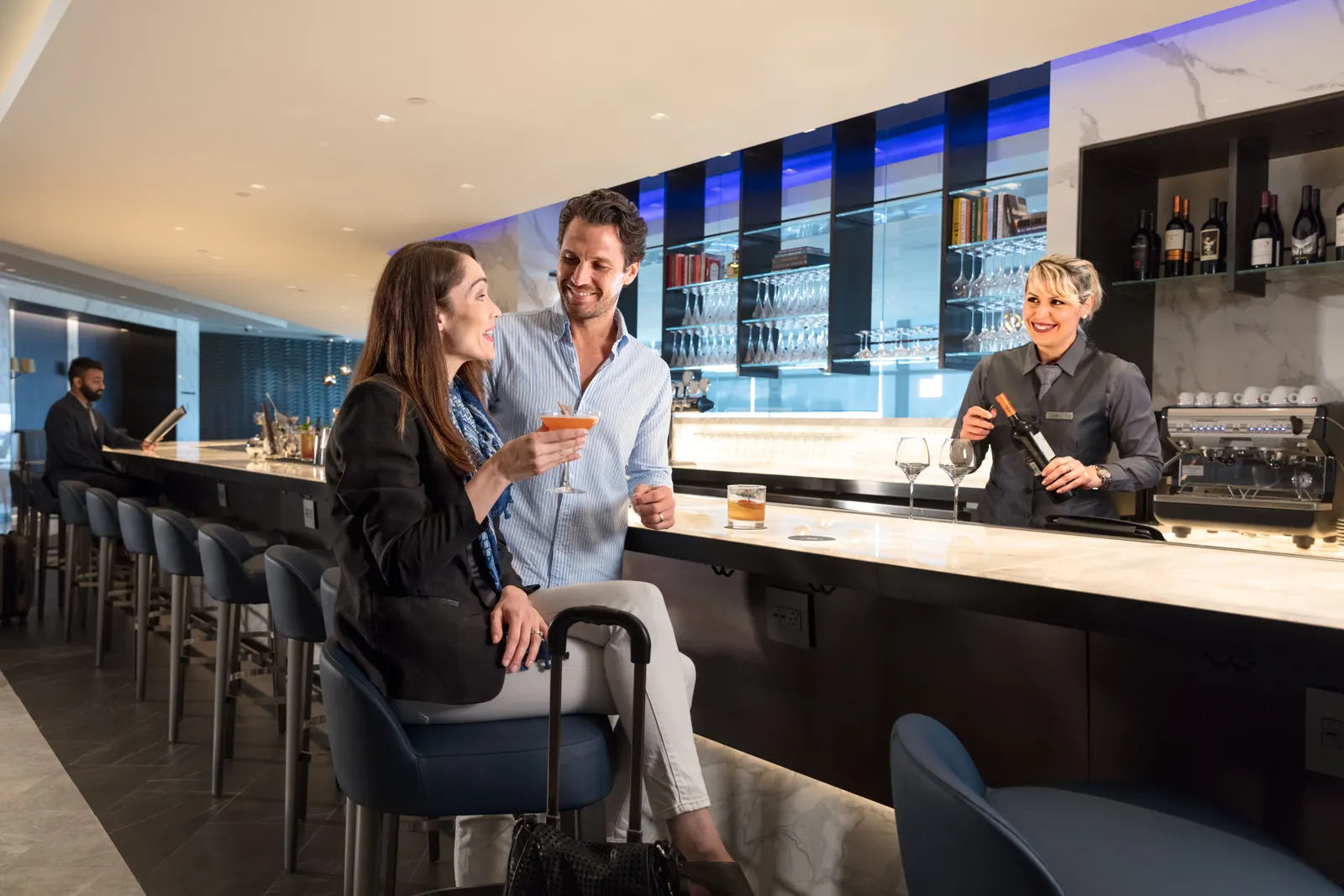 Marble bar with blue stools and back-bar shelving in the United Polaris Lounge at Newark (EWR).