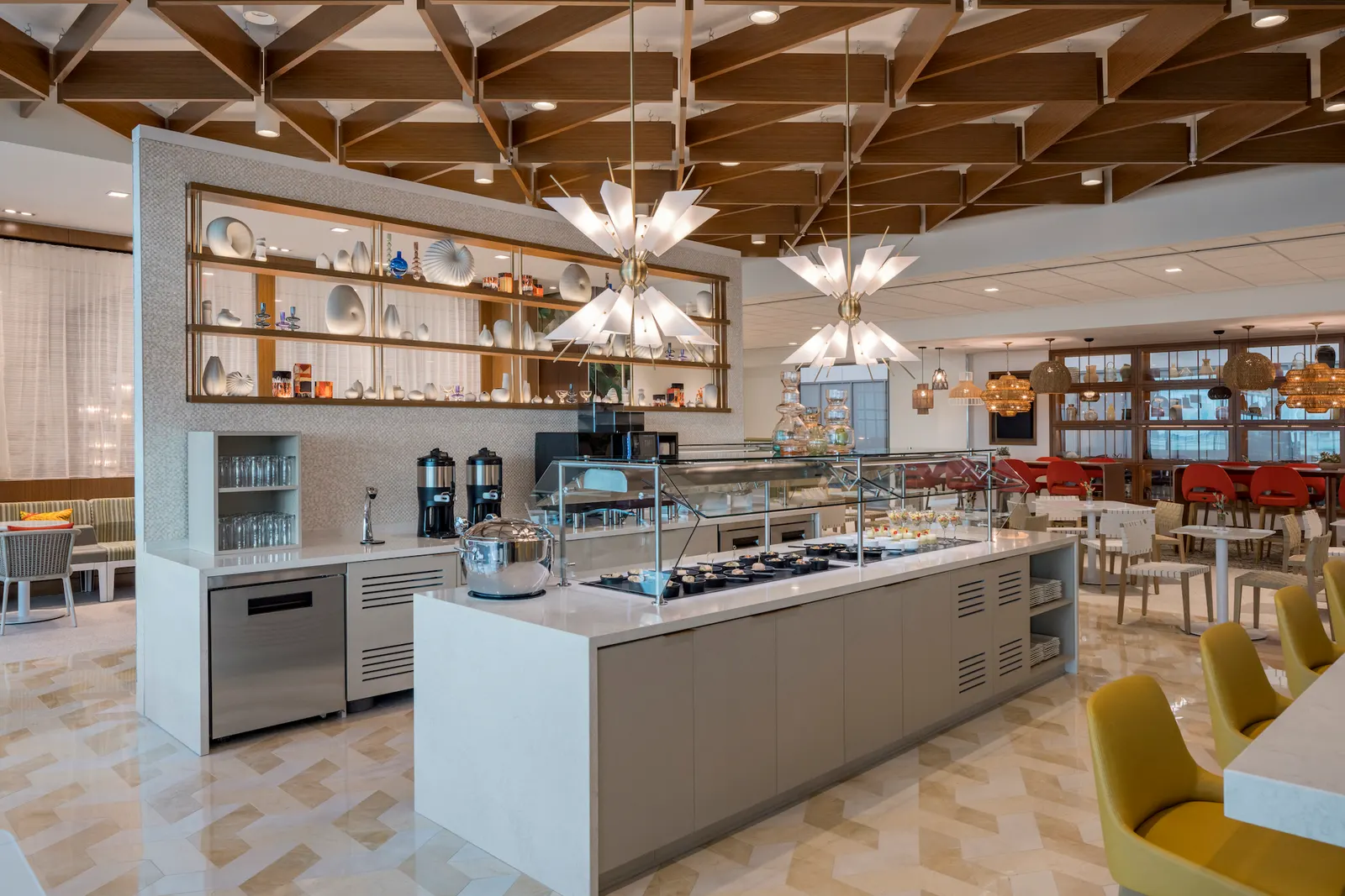 Marble buffet island under starburst pendants and a wood lattice ceiling in the Escape Lounges at Fort Lauderdale-Hollywood International Airport (FLL).