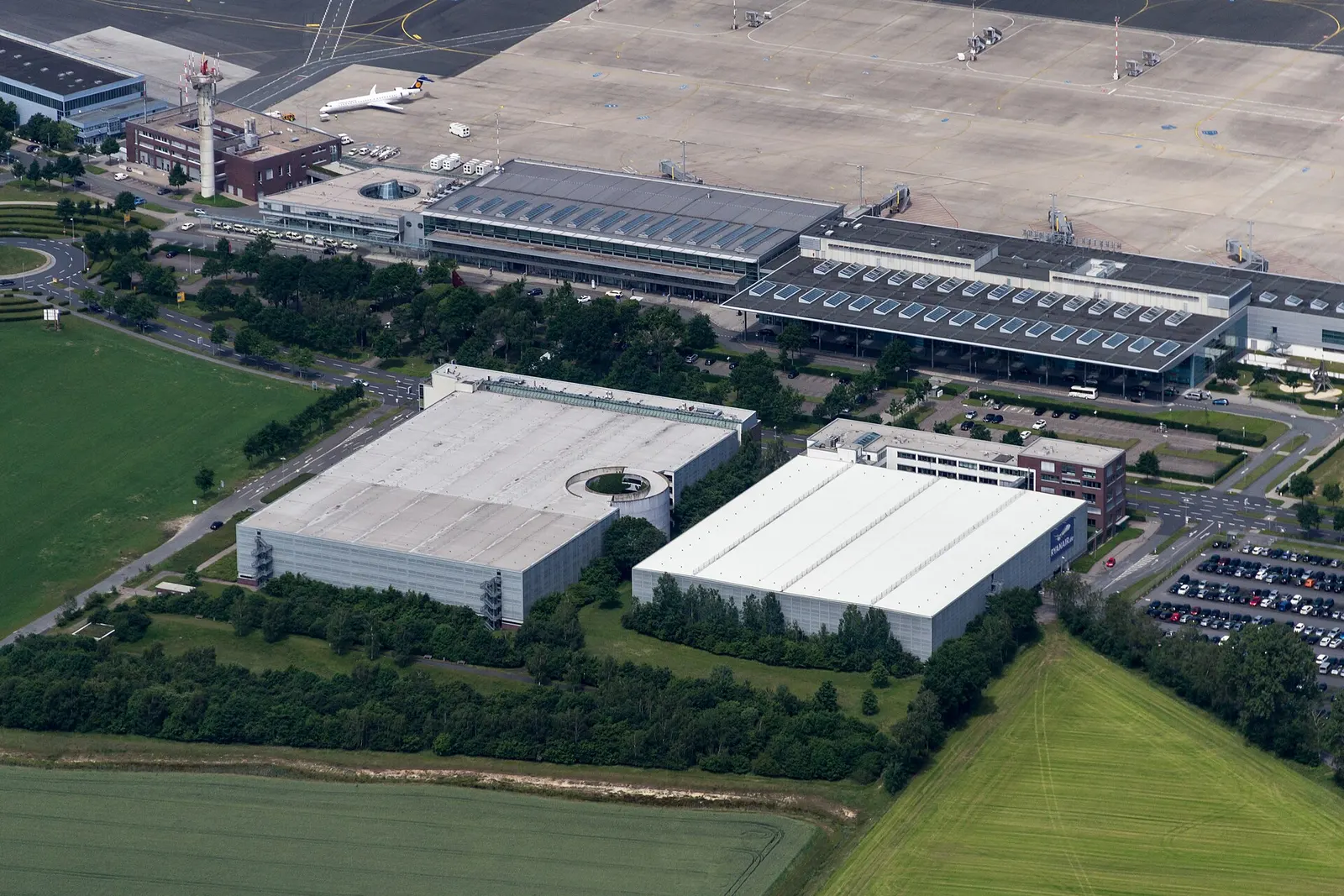 Aerial view of Münster/Osnabrück Airport Terminal 1 and Terminal 2 on the apron, with the control tower and a parked Lufthansa regional jet, Greven, 2014.