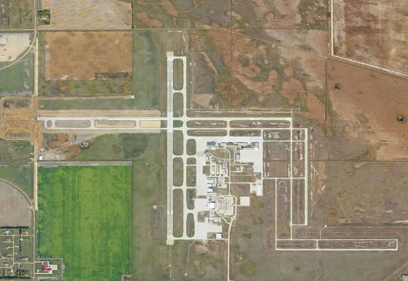 USGS NAIP aerial of Grand Forks International Airport showing the crossed air-carrier runways, east-side UND / passenger campus, and Highway 2