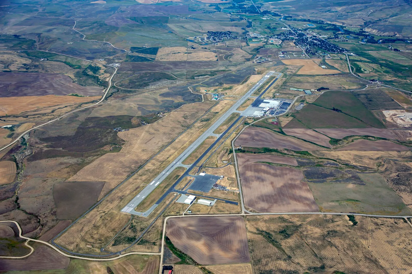 Looking northeast to southwest across Yampa Valley Regional Airport from the FBO end of the Hayden airfield, with the commercial ramp and terminal campus in view.