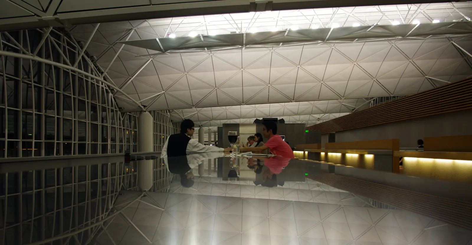 Reflective Long Bar counter at night inside Cathay Pacific The Wing First Class lounge at Hong Kong International (HKG).