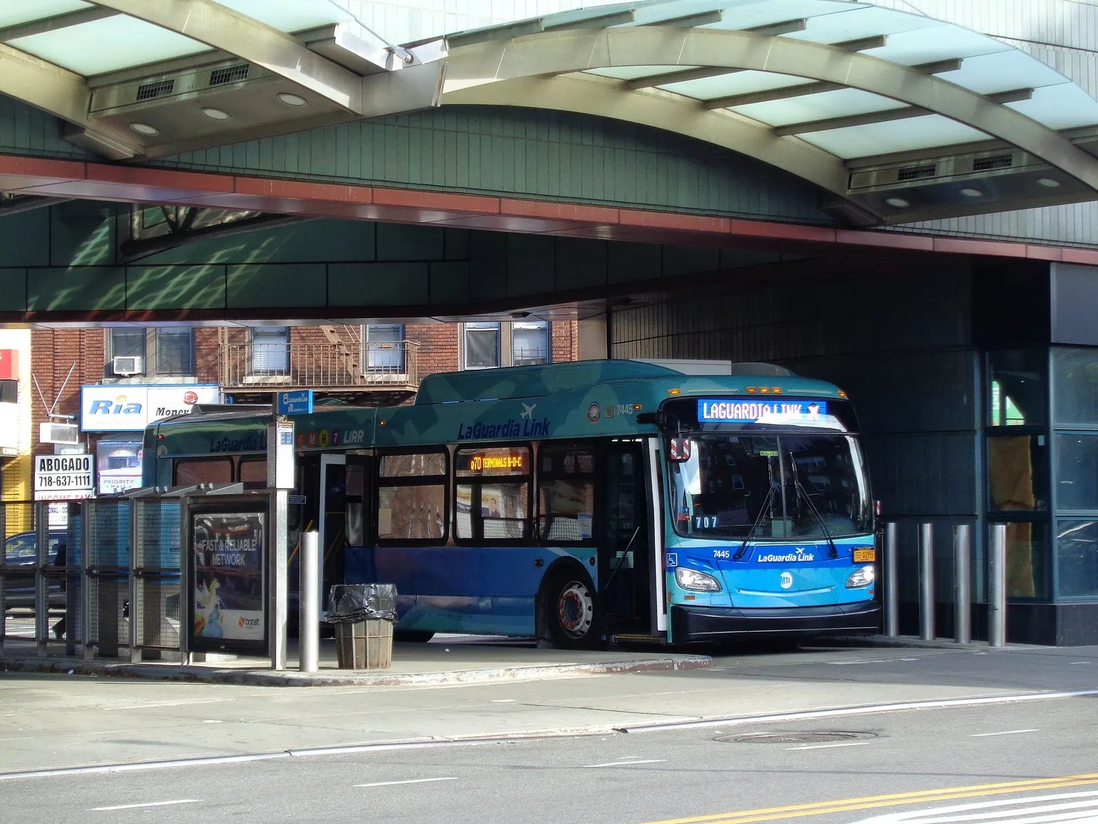 A LaGuardia Airport-bound Q70 SBS bus picking up passengers at the Victor A. Moore Bus Terminal of the Jackson Heights – Roosevelt Avenue / 74th Street subway station, in Jackson Heights, Queens.