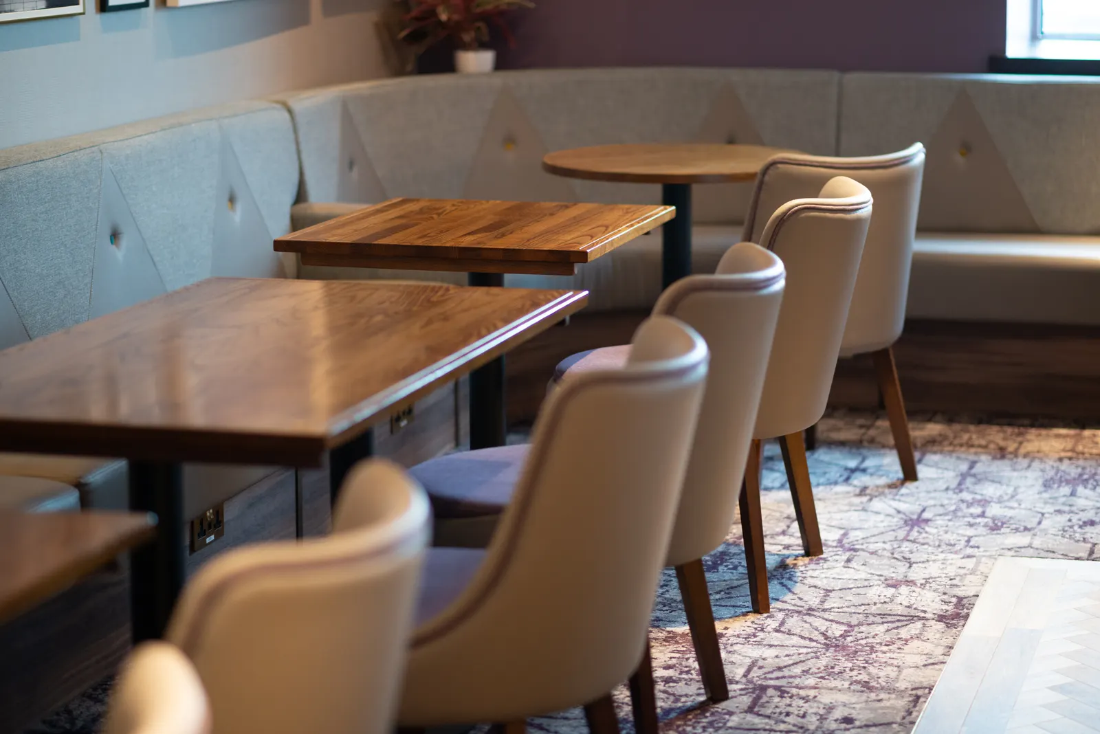 Wooden tables, high-back chairs and tufted banquette in the Aspire Lounge at Humberside Airport (HUY).