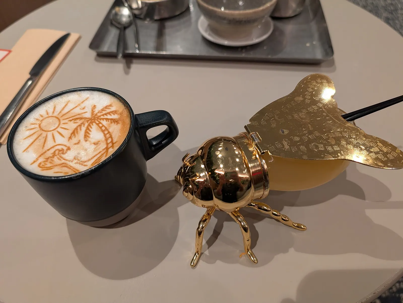 Two drinks at the Capital One Lounge inside Dulles Airport. One the left is a Latte with a beach scene printed on it and on the right is their honey-based signature cocktail. Main Terminal, Dulles Airport, 1 Saarinen Circle, Dulles, Virginia 20166.
