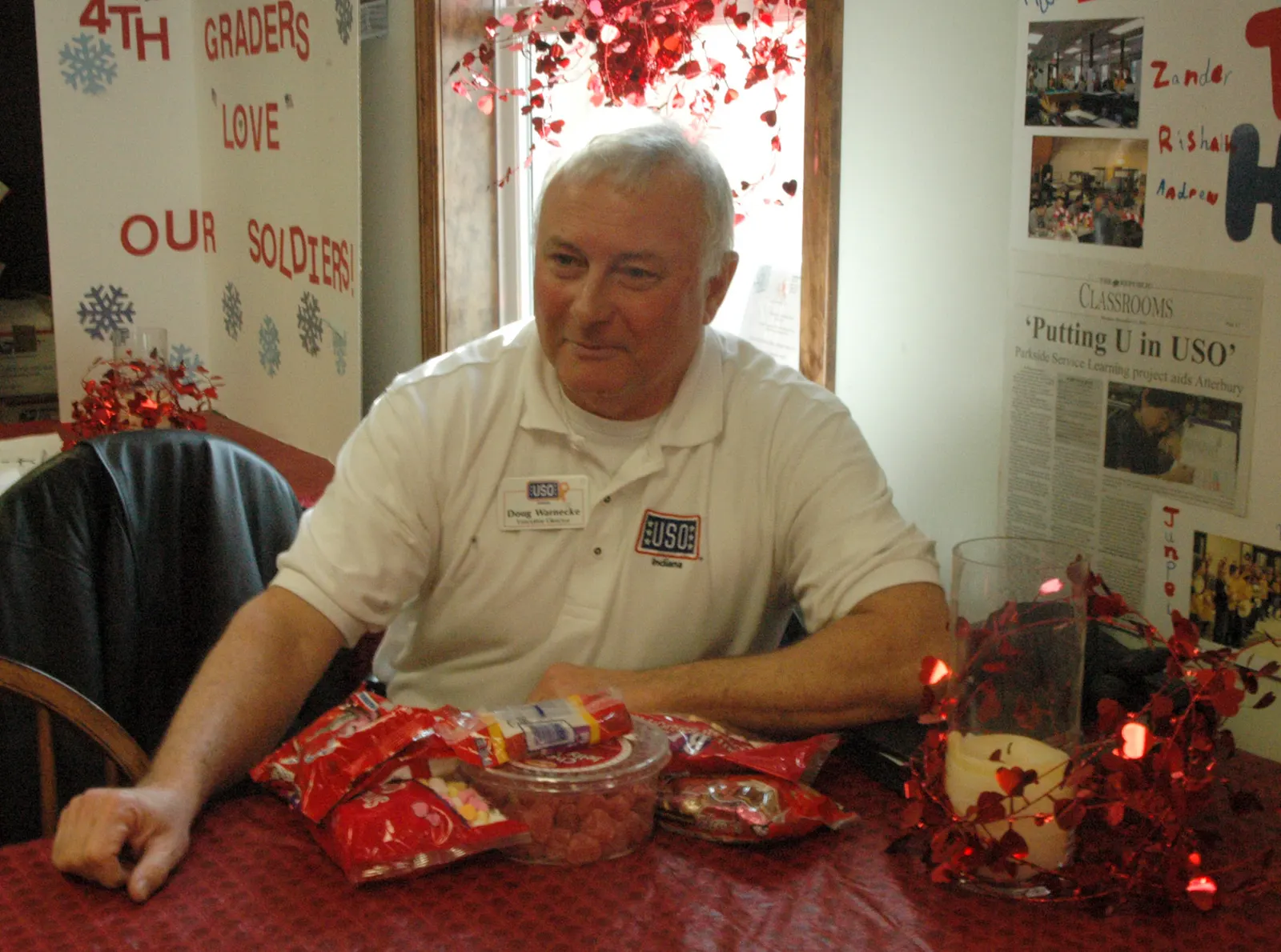 Doug Warnecke, executive director of the USO of Indiana, poses with Valentine's Day treats given by students from Parkside Elementary School in Columbus, Ind., during an event at the Camp Atterbury USO, Feb 8. Twenty third-grade students delivered Valentine's Day cards and toiletry items to soldiers