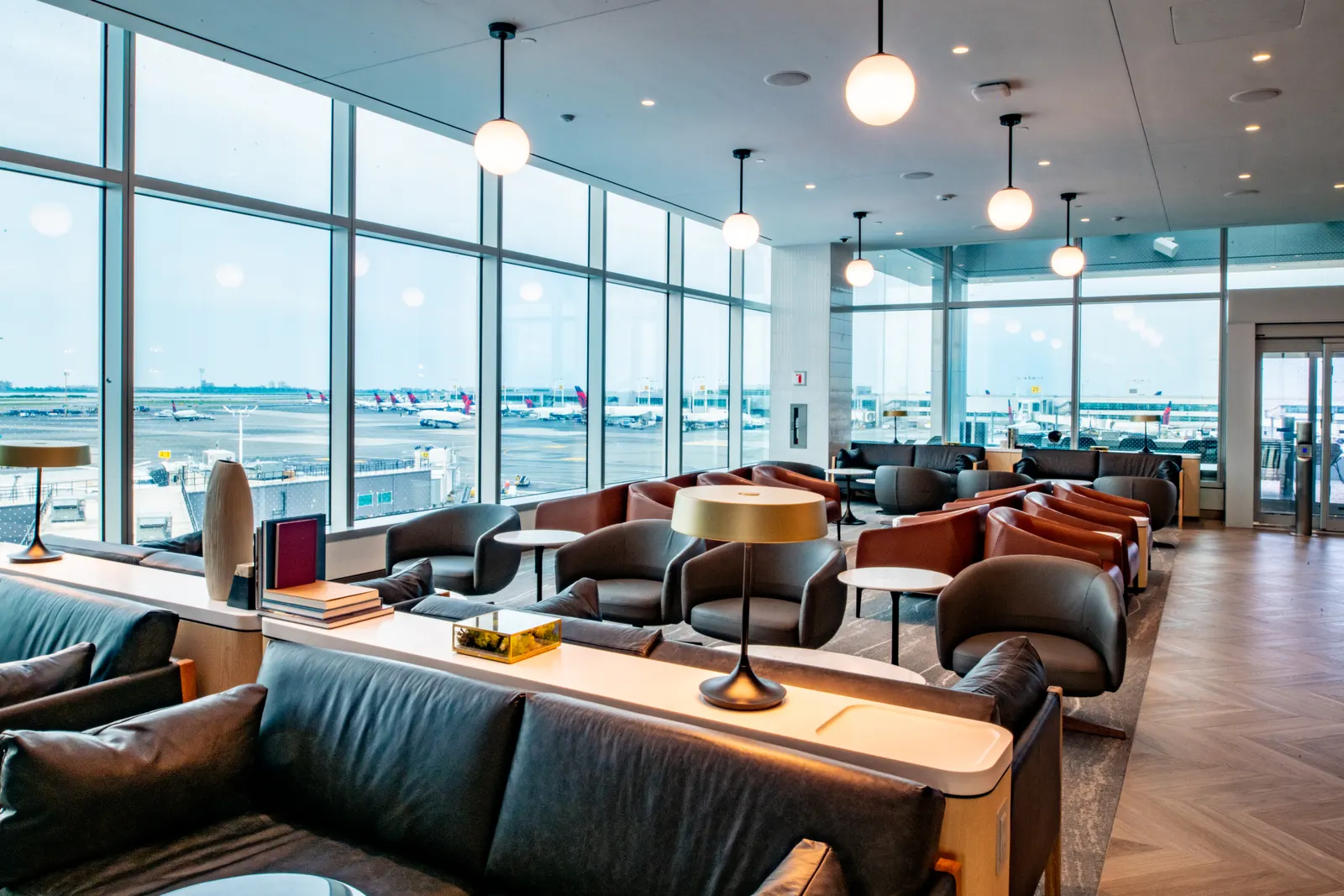 Lounge seating beside large windows overlooking the airfield at the Delta Sky Club at JFK.