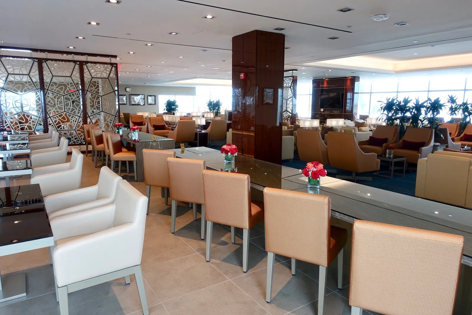 Tan leather seating, communal marble table and honeycomb divider in the Emirates Lounge at New York JFK Terminal 4.