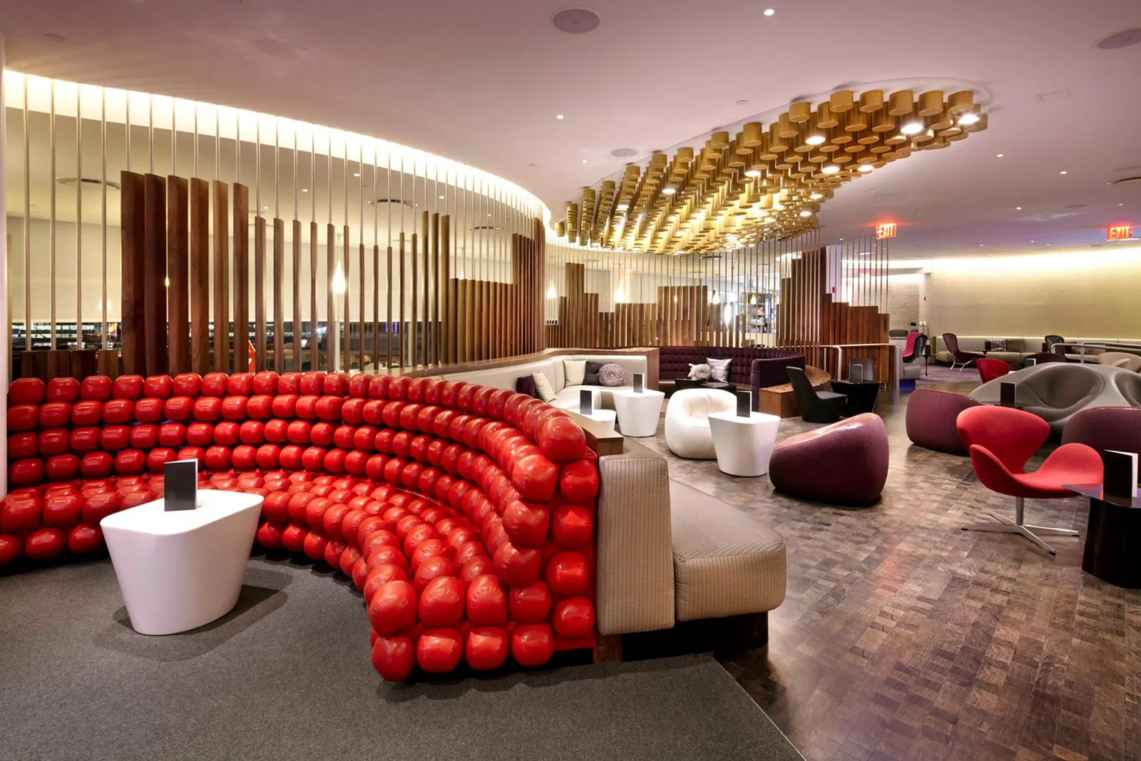 Central cocktail lounge with hanging golden cylinders in the Virgin Atlantic Clubhouse at New York JFK Terminal 4.