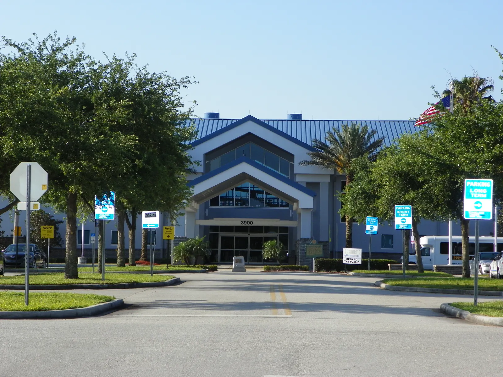Two-story Lakeland Linder passenger terminal with a tiled roof, porte-cochère, and surface parking in front.