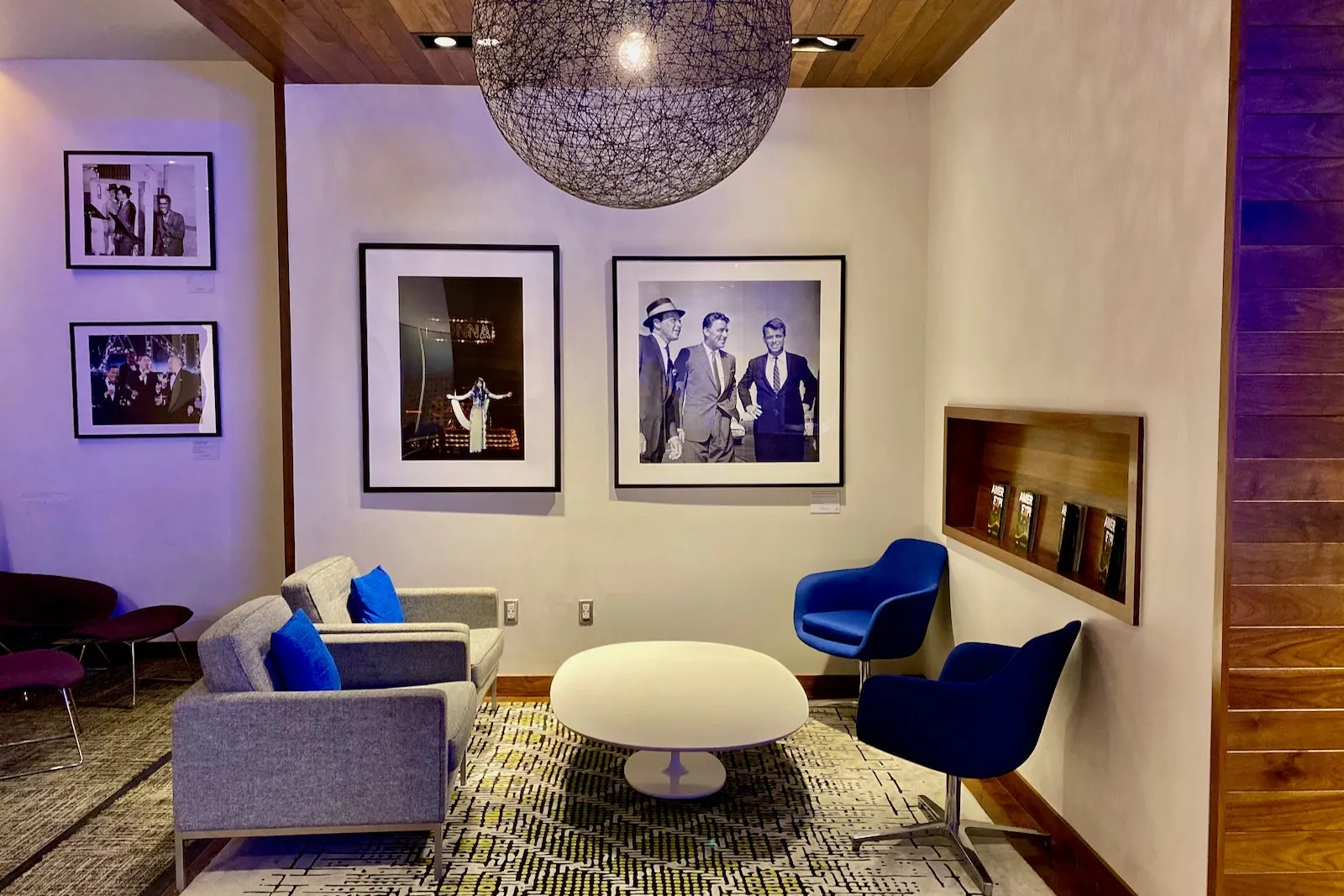 Mid-century seating nook with Rat Pack wall photos in The Centurion Lounge at Las Vegas Harry Reid (LAS).
