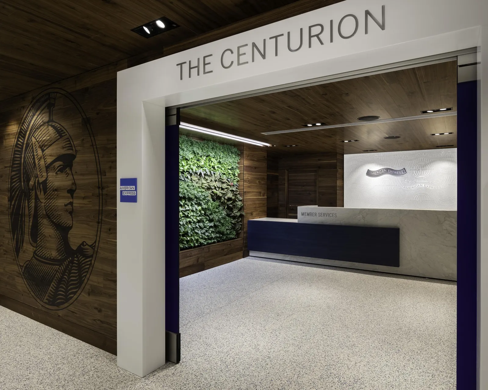 White-framed Centurion Lounge entrance with Member Services desk, living green wall and American Express logo panel at Los Angeles International Airport Tom Bradley Terminal (LAX).