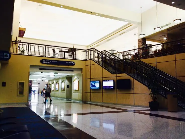 Two-story LCH lobby with a staircase, ticketing and all-gates sign, and an empty polished floor.