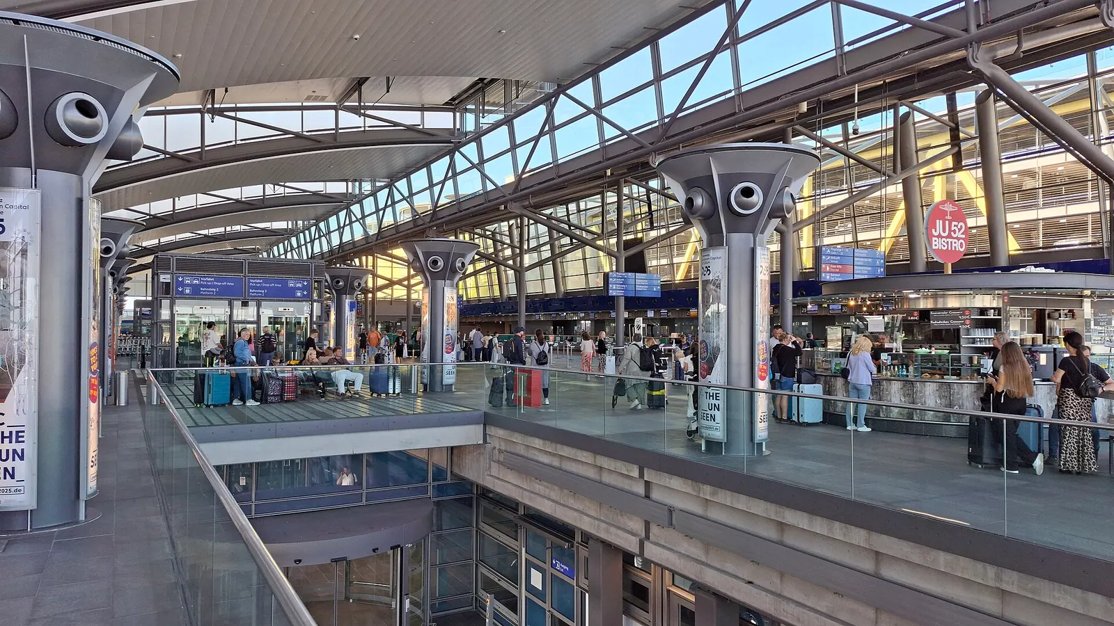 Check-in gallery at Leipzig/Halle Airport with the Ju 52 Bistro sign, glass railings, and passengers with luggage under the steel roof.