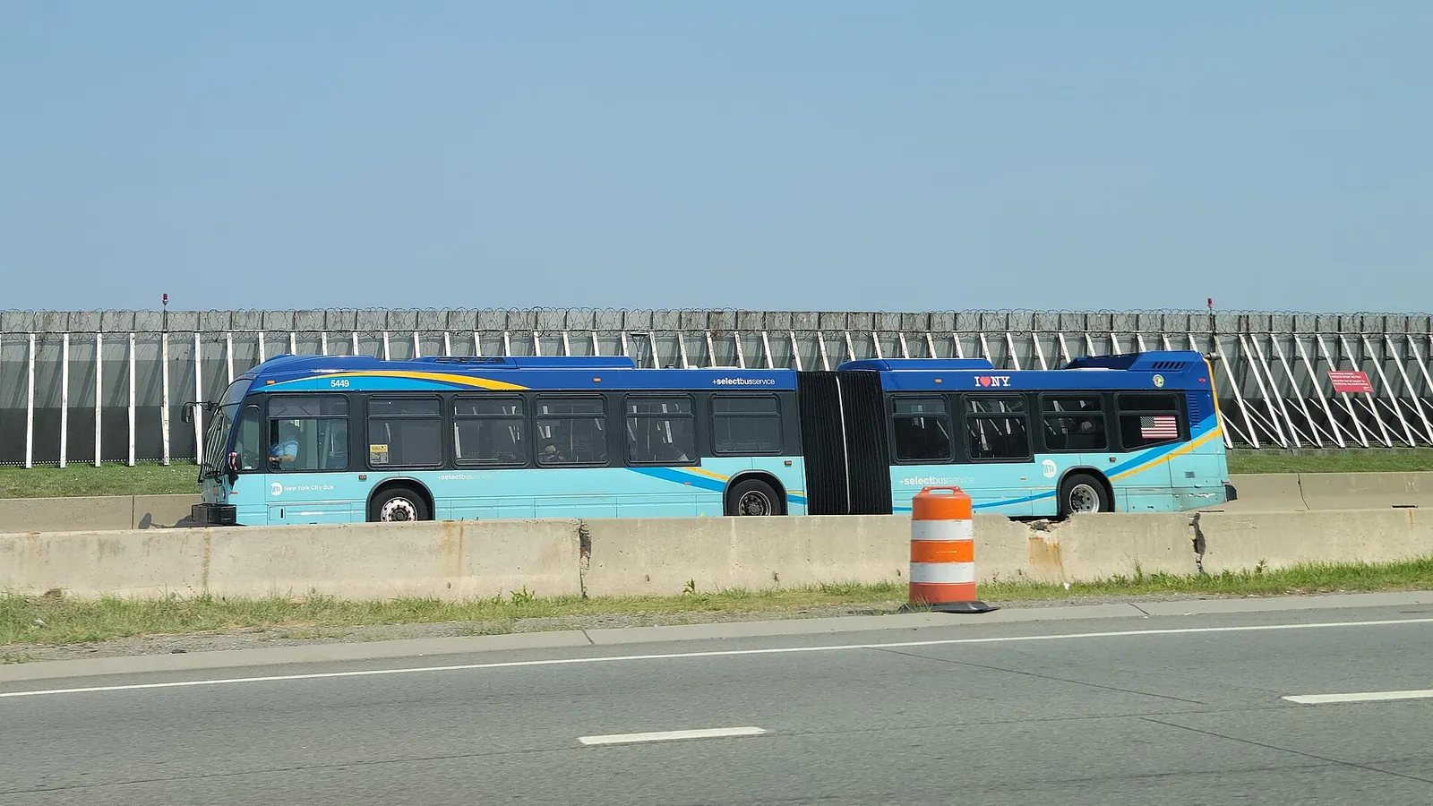 A West Side–Broadway-106th Street-bound M60 SBS bus traveling west on Runway Drive through the west end of LaGuardia Airport, looking from the Grand Central Parkway east of 82nd Street in East Elmhurst, Queens. The M60 route technically terminates at Terminal C; this bus will head north to the Marin