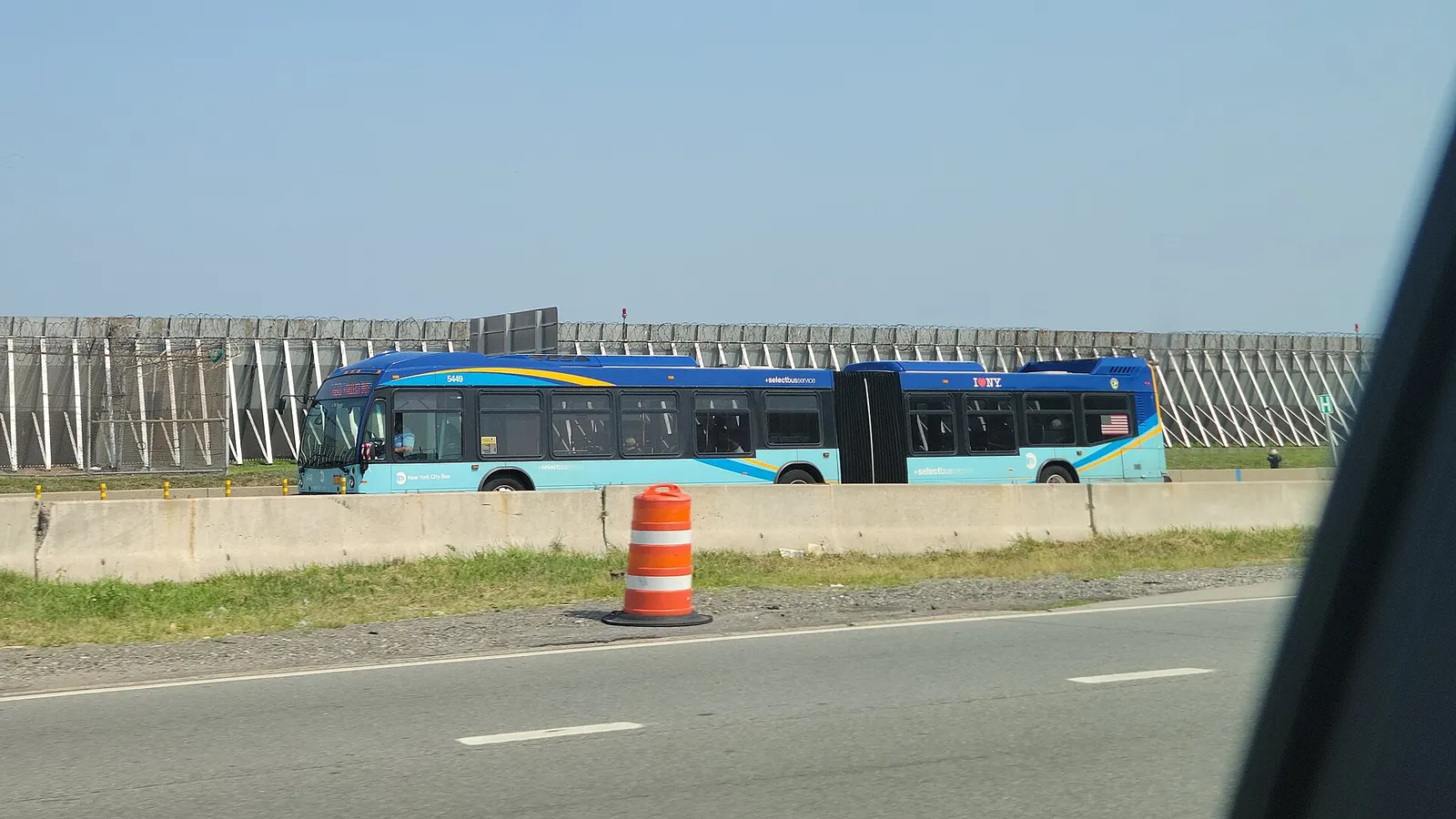 A West Side–Broadway-106th Street-bound M60 SBS bus traveling west on Runway Drive through the west end of LaGuardia Airport, looking from the Grand Central Parkway east of 82nd Street in East Elmhurst, Queens. The M60 route technically terminates at Terminal C; this bus will head north to the Marin
