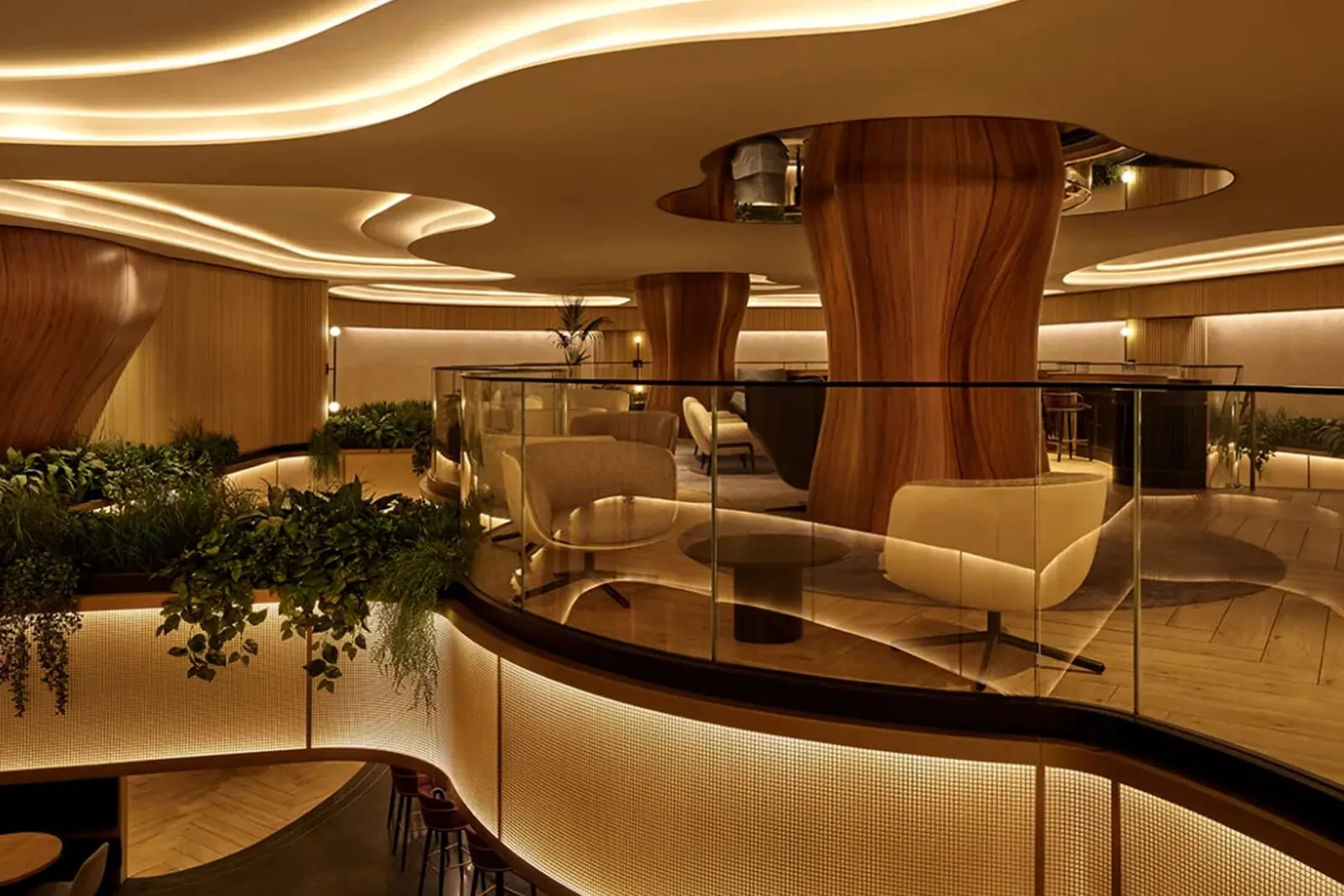 Upper-level seating with cream swivel chairs, sculptural wood columns and hanging greenery in the Chase Sapphire Lounge at LGA.