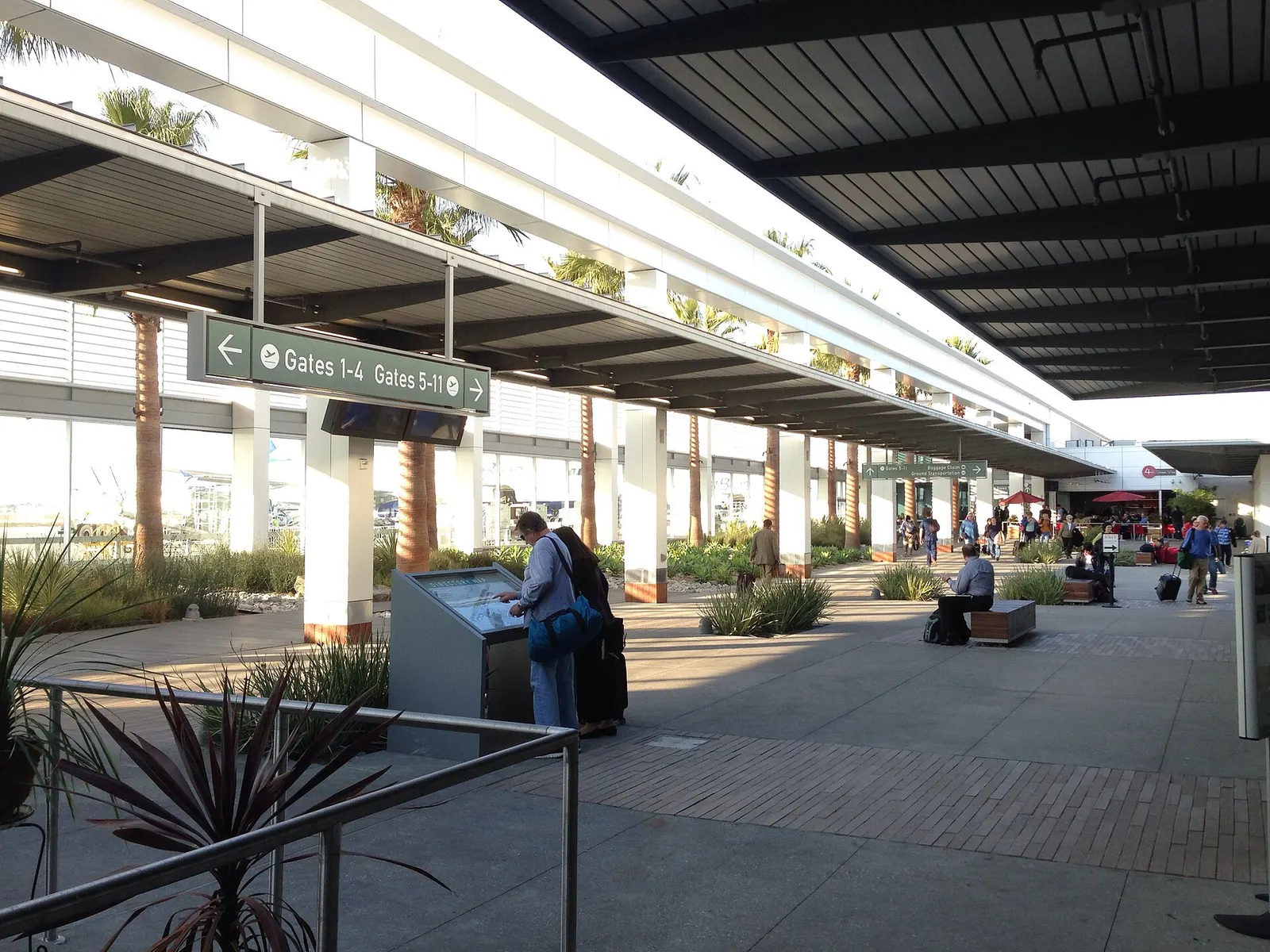 Open-air garden between Long Beach Airport’s North and South concourses, with palm trees and outdoor seating looking toward the gate buildings.