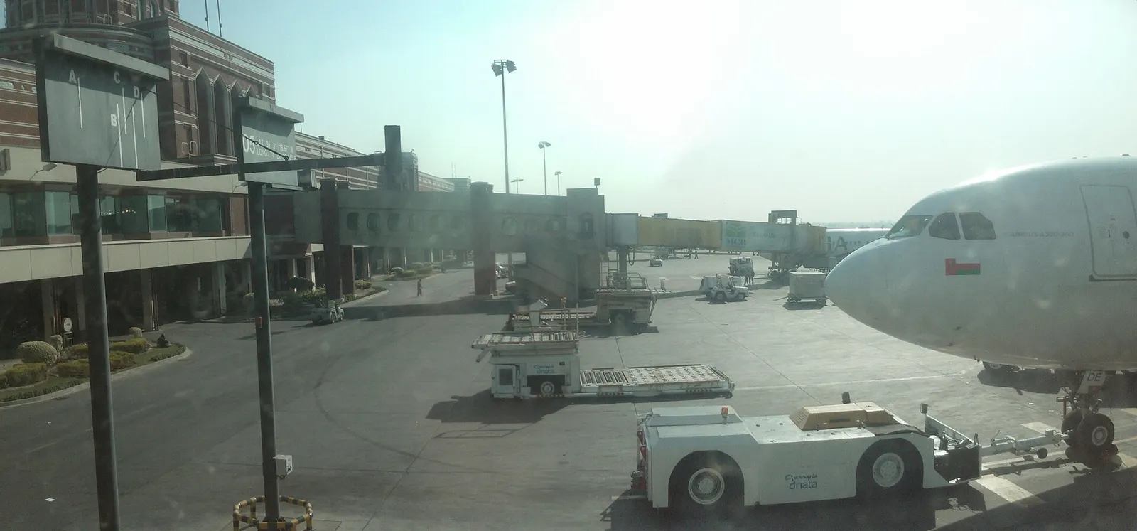 Airside apron and a Shaheen Air Airbus at a jet bridge, photographed from the Allama Iqbal International departure lounge.