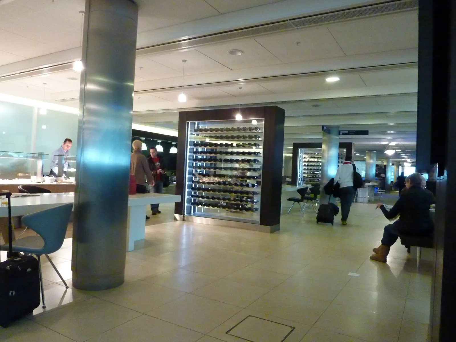 Glass-enclosed wine rack divider beside a buffet counter and tiled walkway inside the British Airways Galleries Club Lounge at Heathrow Terminal 5 (LHR).