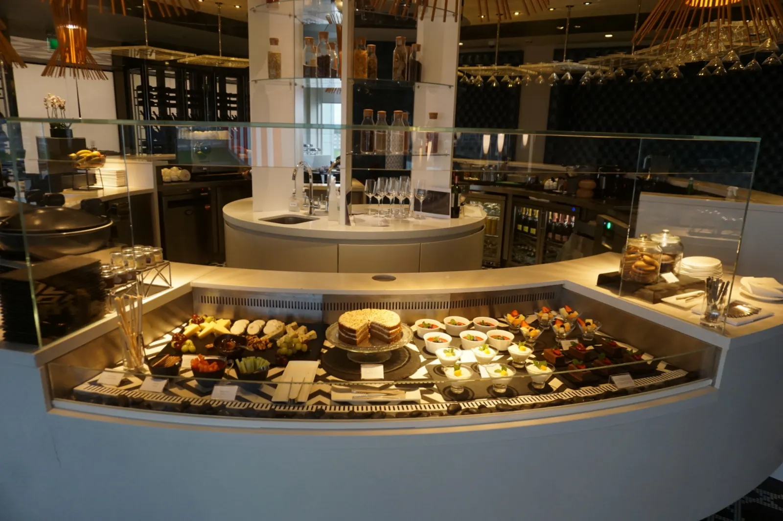 Buffet counter with cheeses, cakes, and desserts inside the Qatar Airways Premium Lounge at Heathrow Terminal 4 (LHR).