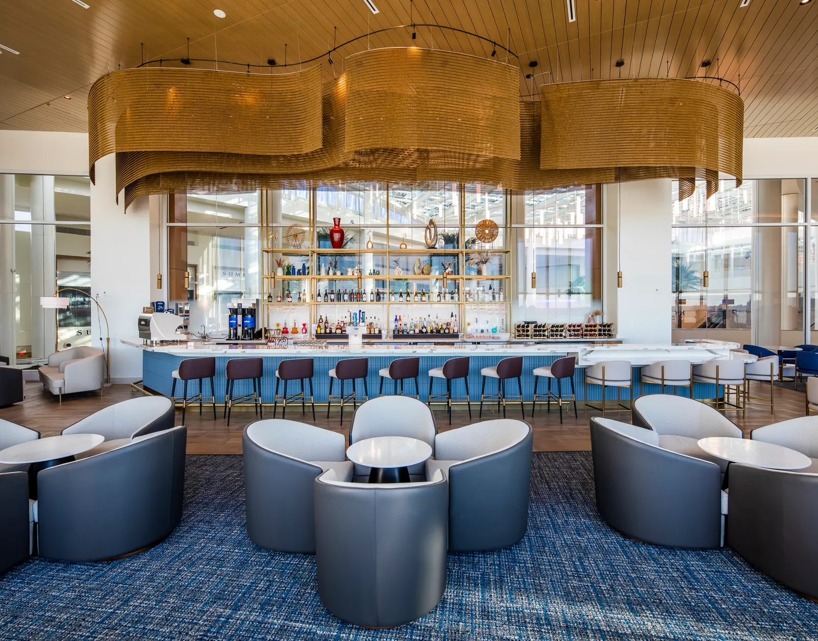 Two-story entry and family lounge with sculptural tree in Plaza Premium Lounge at Orlando Terminal C (MCO).