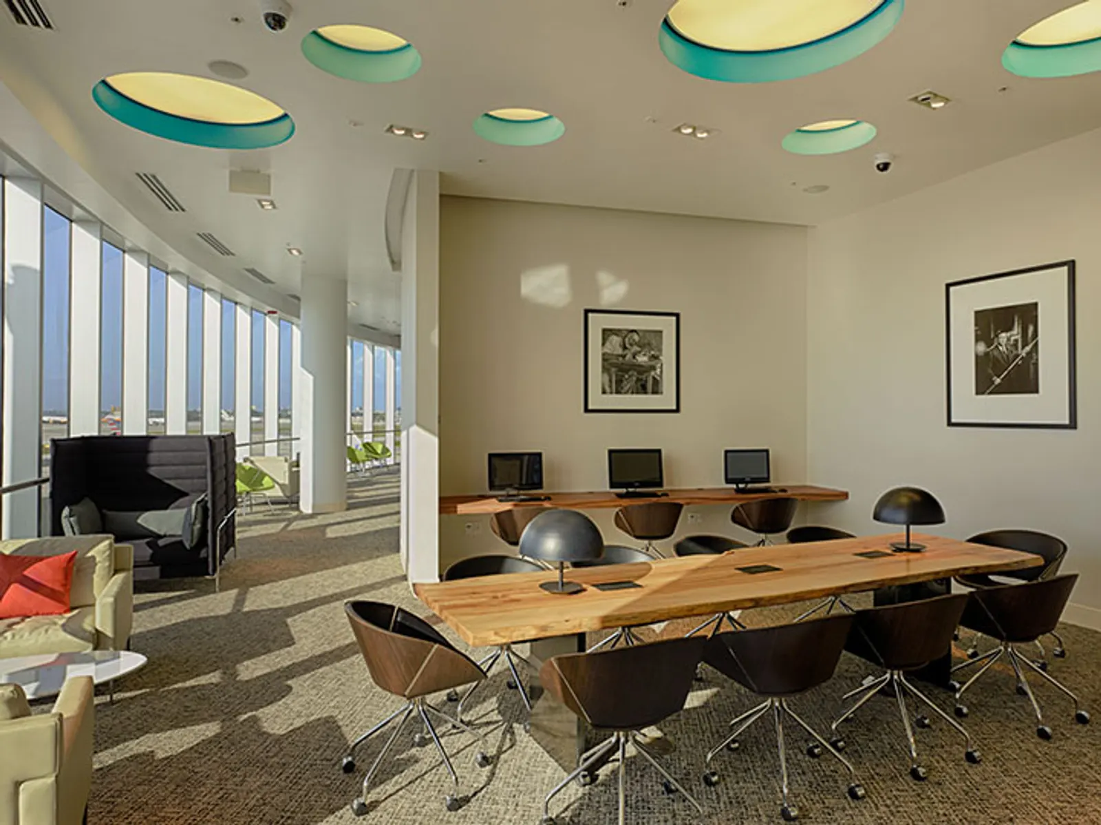 Work spaces with communal table and tarmac-facing windows in The Centurion Lounge at Miami International Airport (MIA).