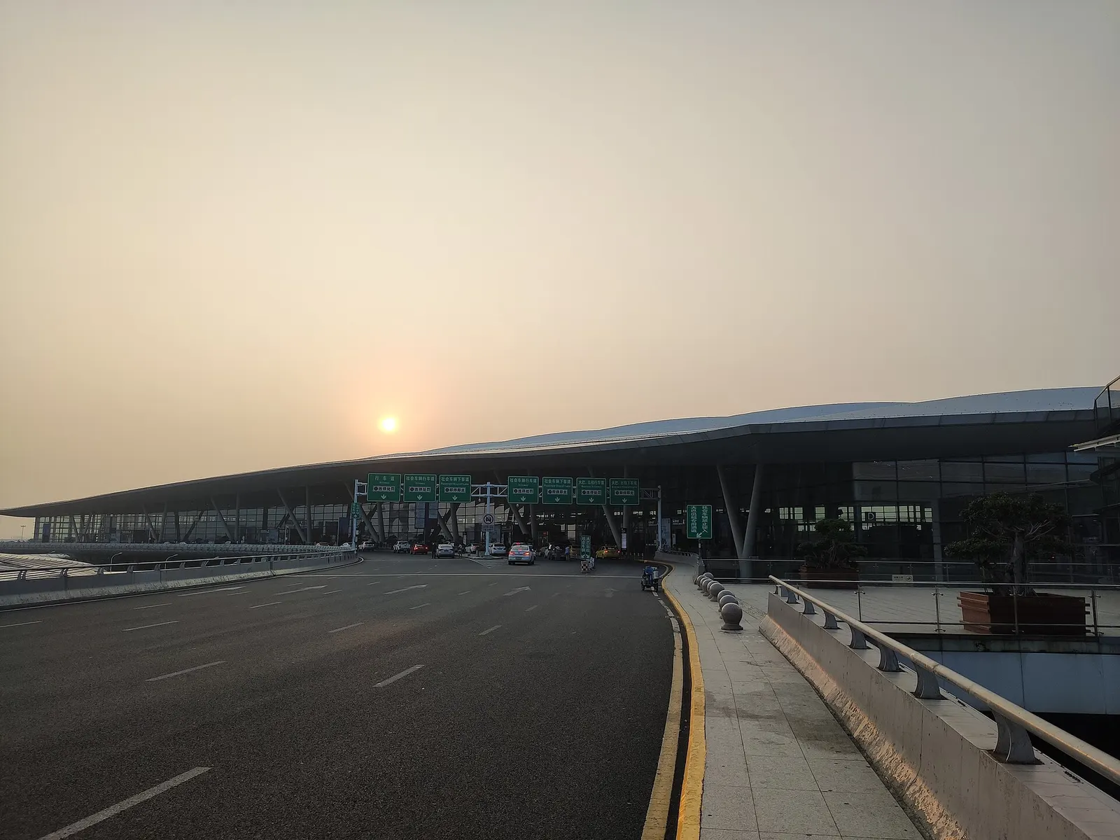 Morning exterior of Nanjing Lukou Terminal 2 with the curved glass facade and forecourt.