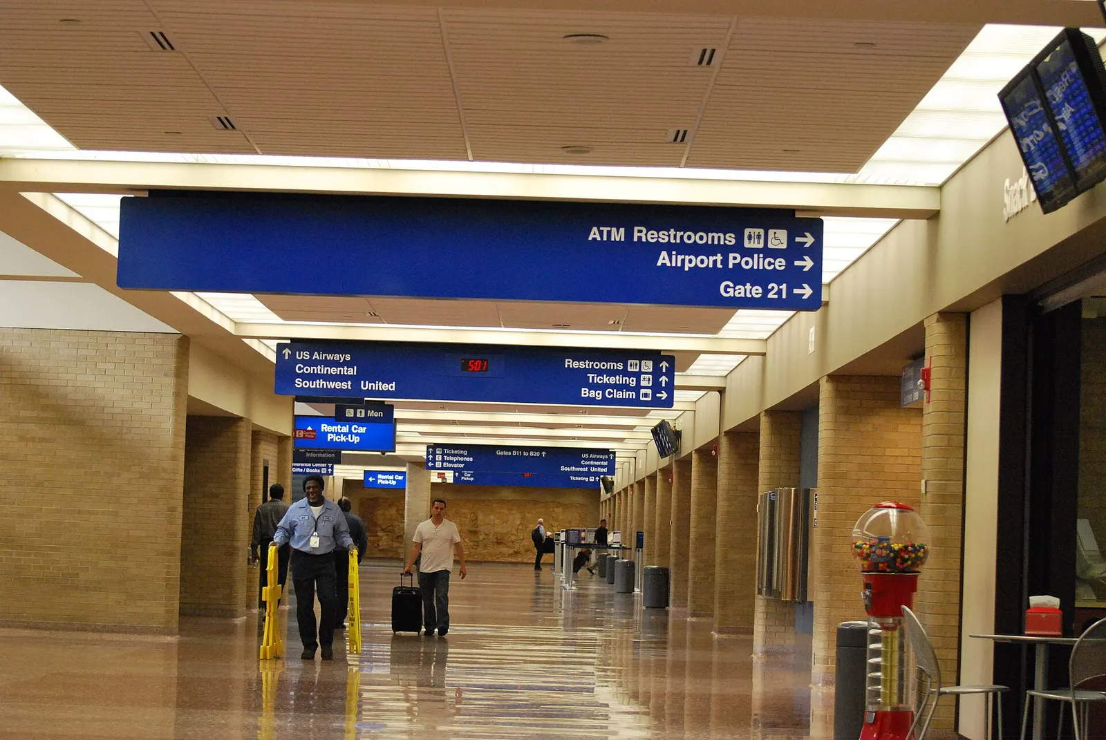 Historic Eppley landside hall with tan brick, a gumball machine, and blue signs listing US Airways, Continental, Southwest, United, and Gates B11 to B20.