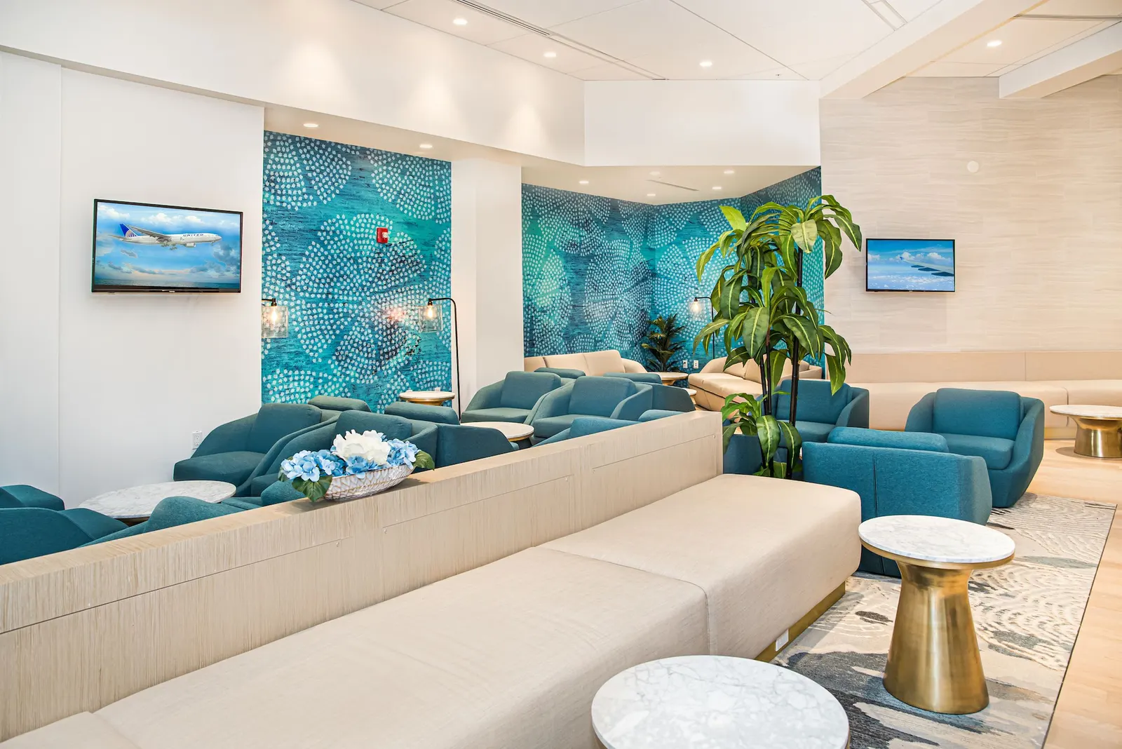 Lounge seating with tropical mural in the Escape Lounge at Palm Beach International Airport (PBI).
